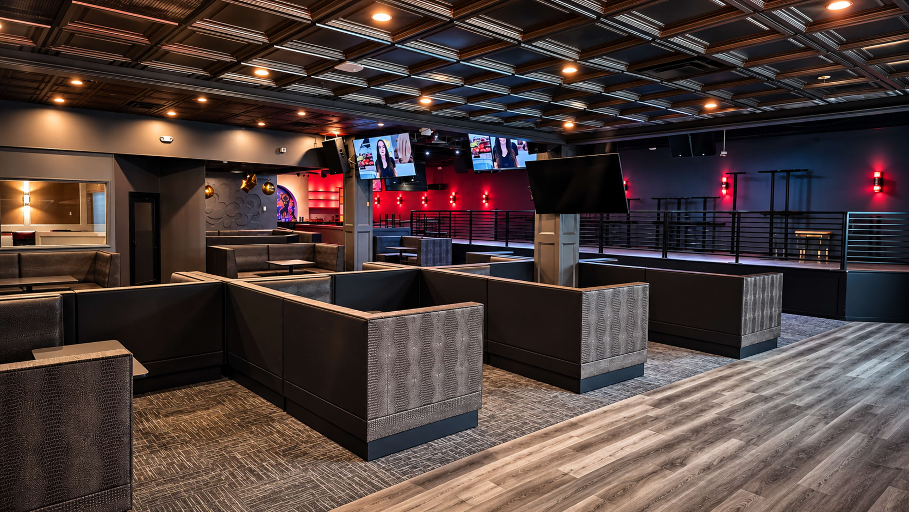The image shows a modern lounge area featuring sectional seating, multiple televisions, and a stylish ceiling with a grid design.