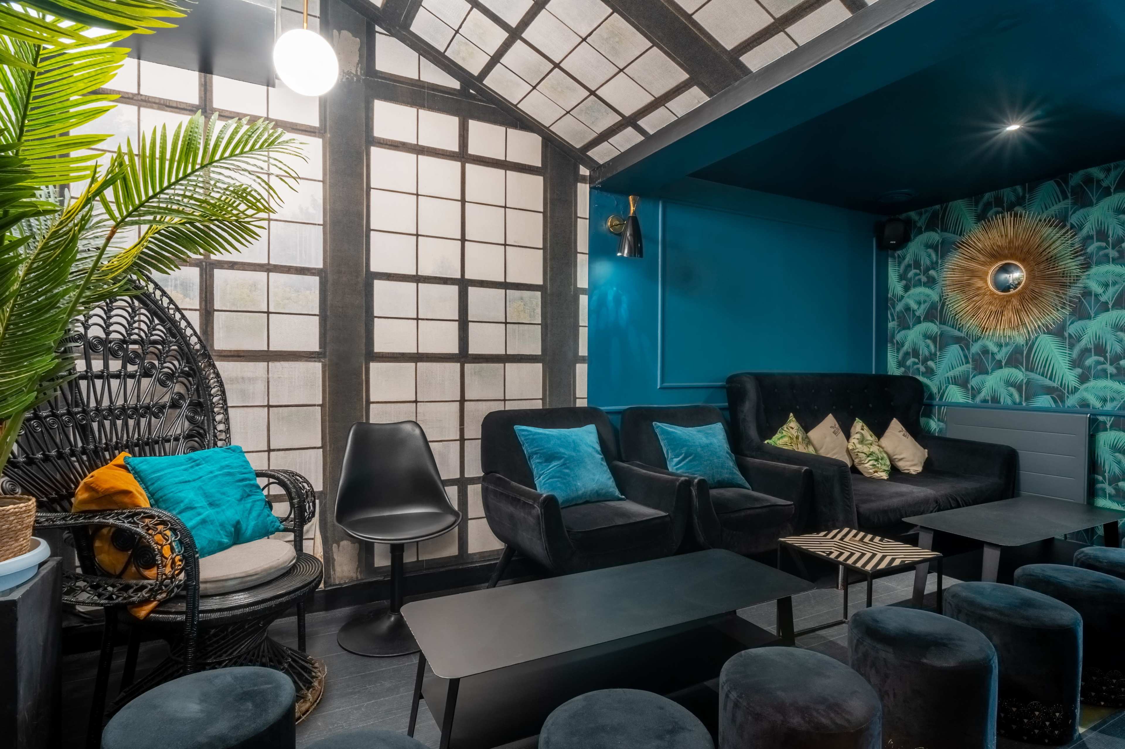 A modern lounge with dark furniture, a distinctive patterned wall, and large windows allowing natural light to fill the space.
