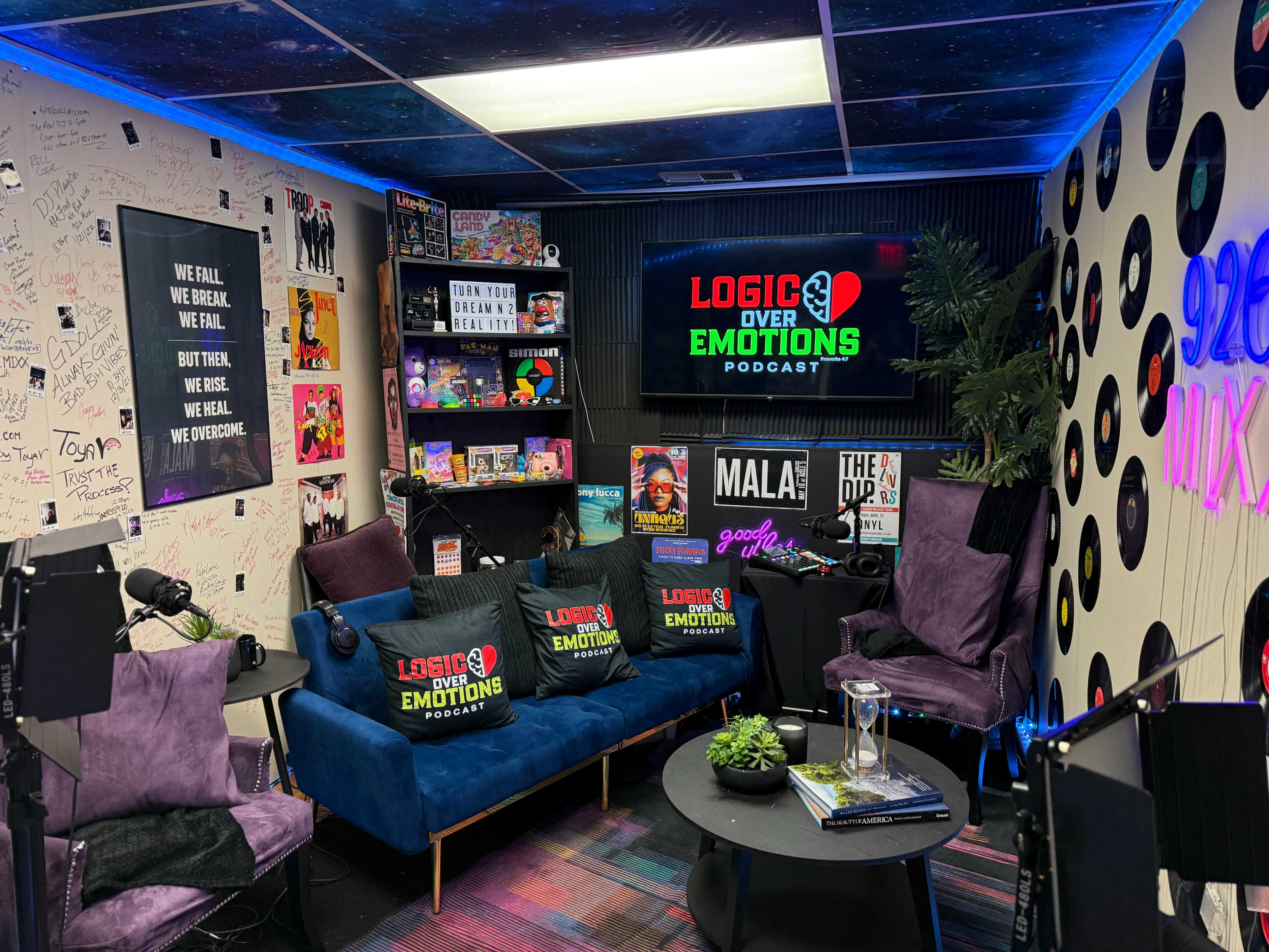 The image depicts a podcast studio featuring purple chairs, a vibrant carpet, and a wall adorned with graffiti and posters related to the show "Logic Over Emotions."