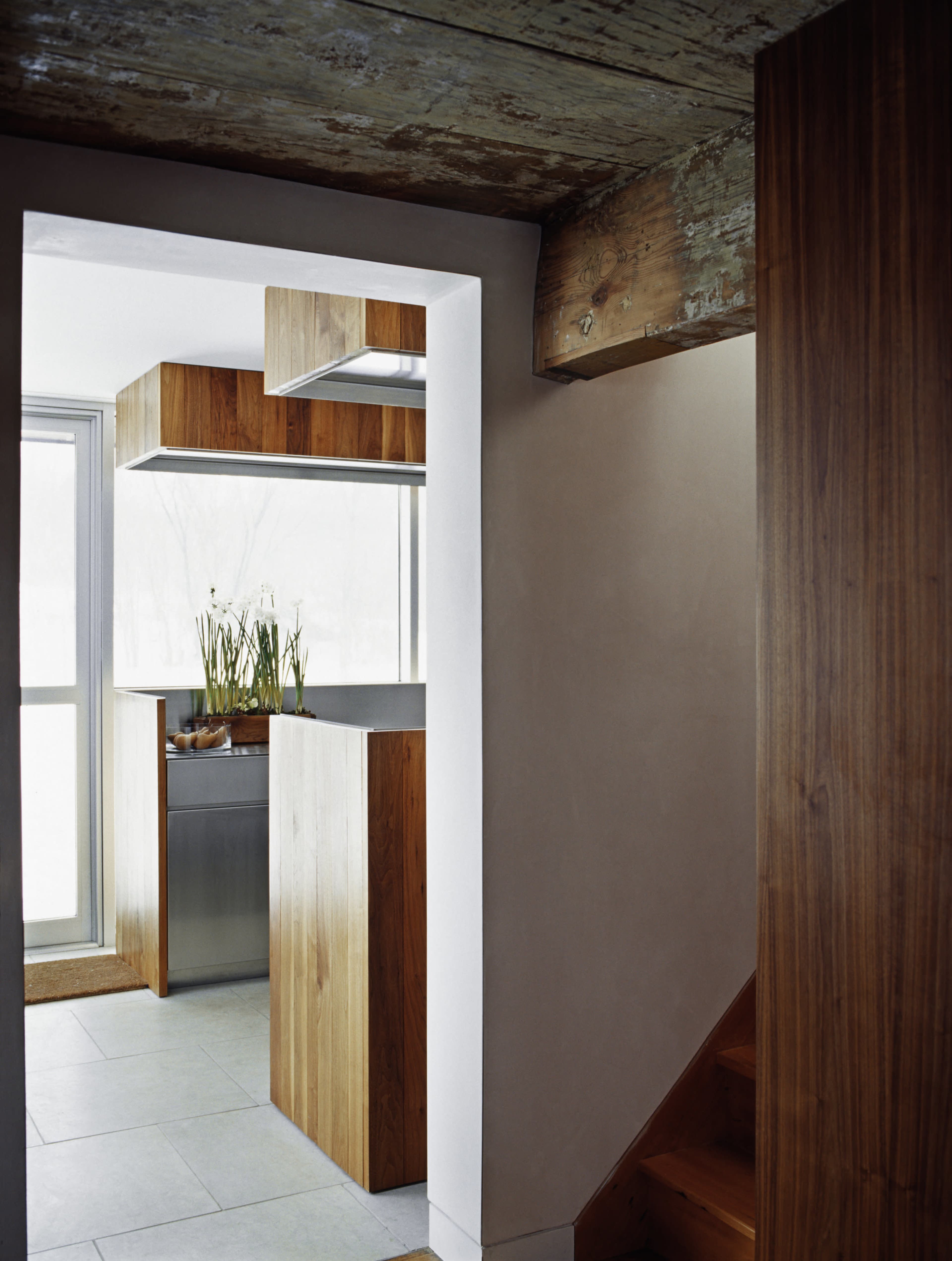 A modern kitchen with wooden cabinetry and a stairway leading to an upper level.