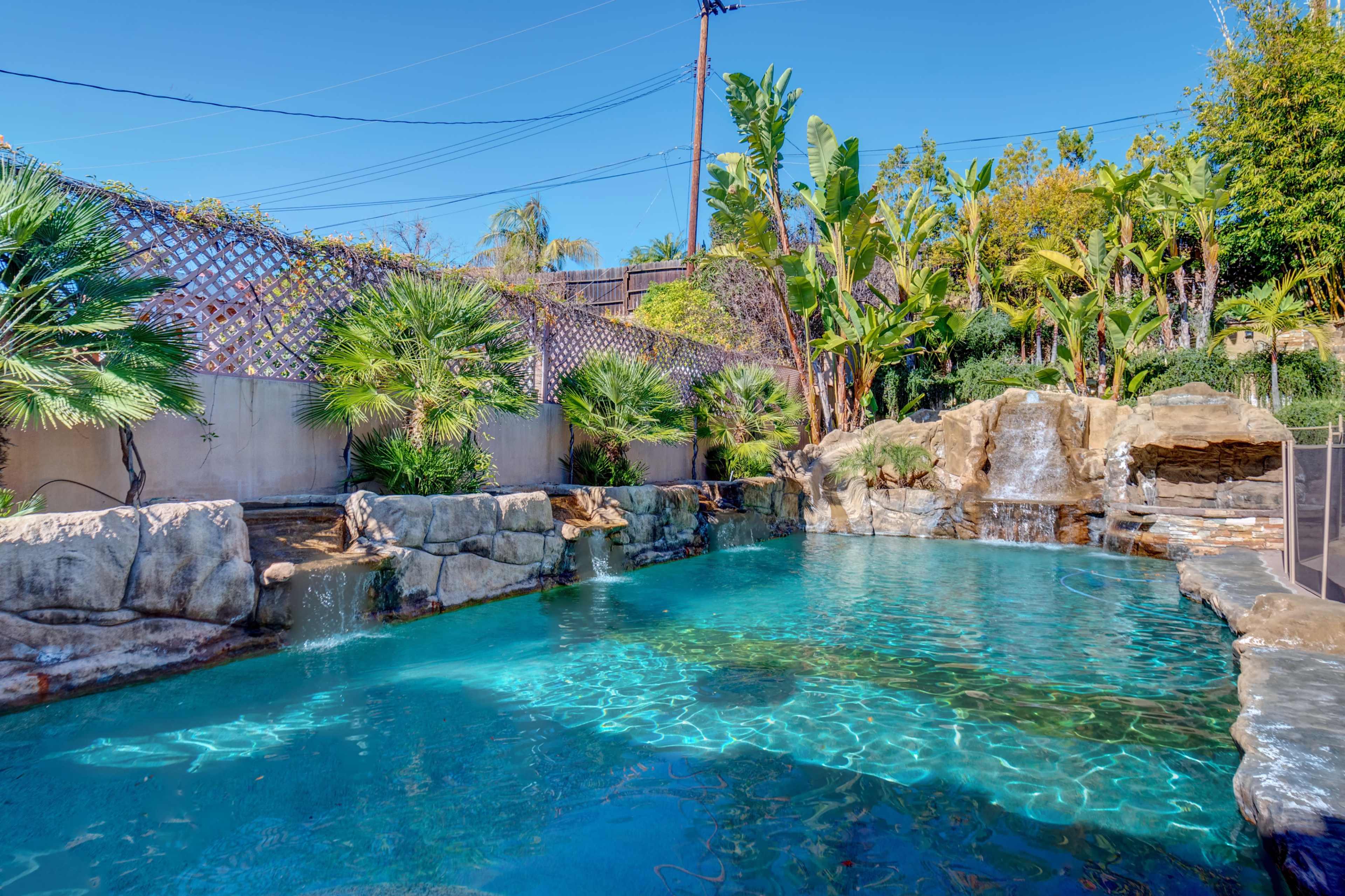 A landscaped pool area surrounded by rock formations and tropical plants.