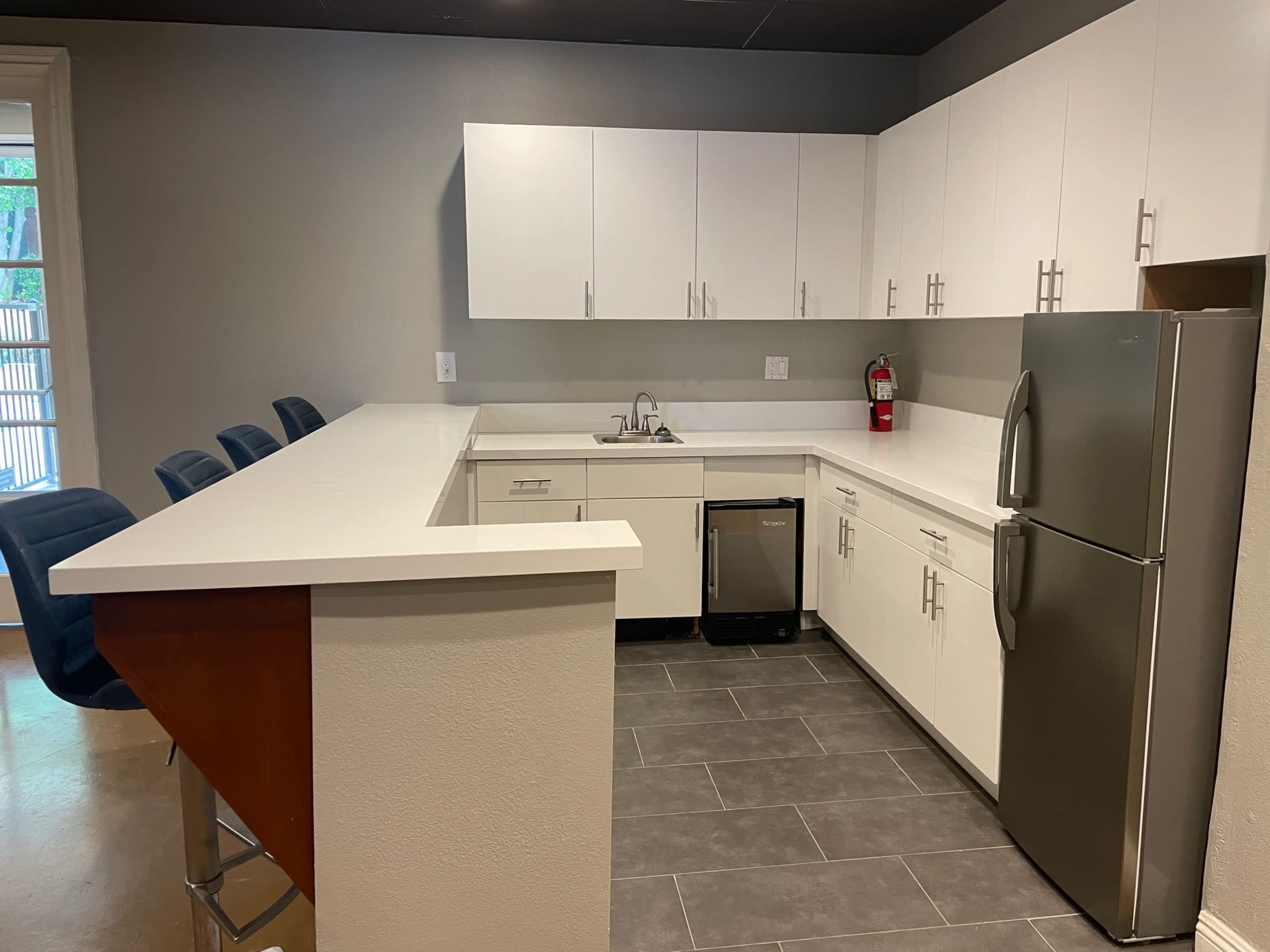 A modern kitchen features white cabinets, stainless steel appliances, and a countertop with seating at one end.