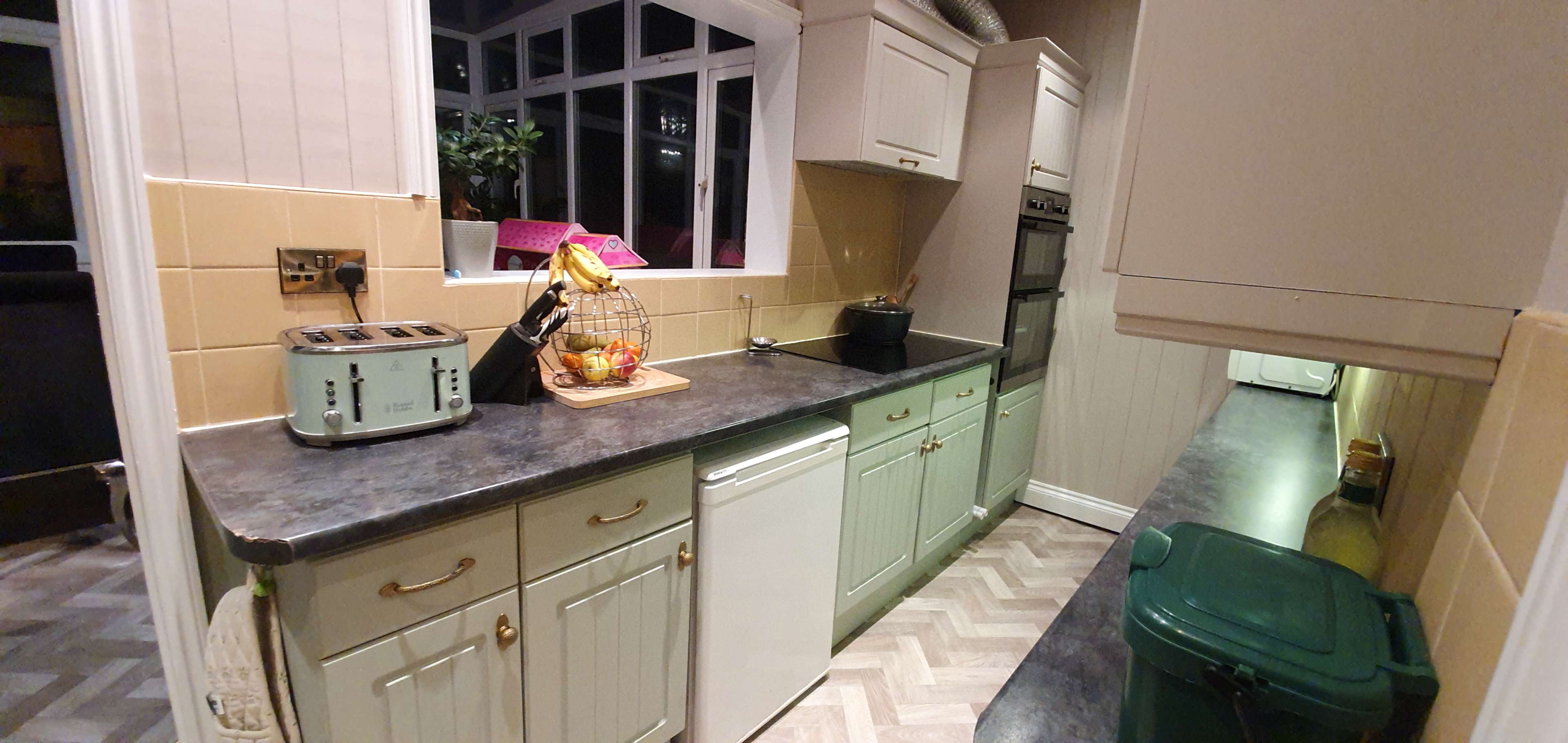 A modern kitchen with a counter, appliances, and a window allowing natural light to enter.