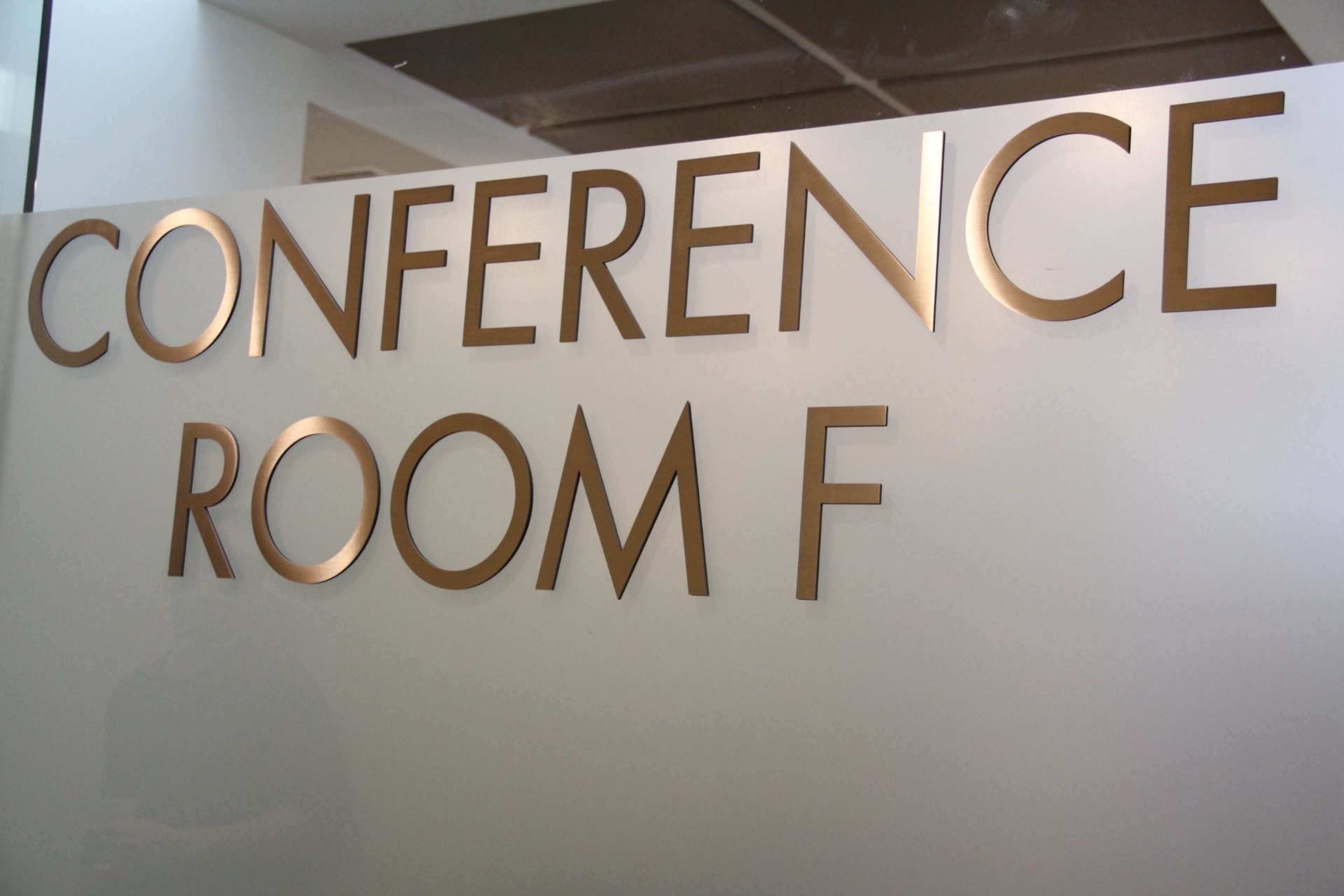 A clear glass door with the words "CONFERENCE ROOM F" displayed in large, gold letters.