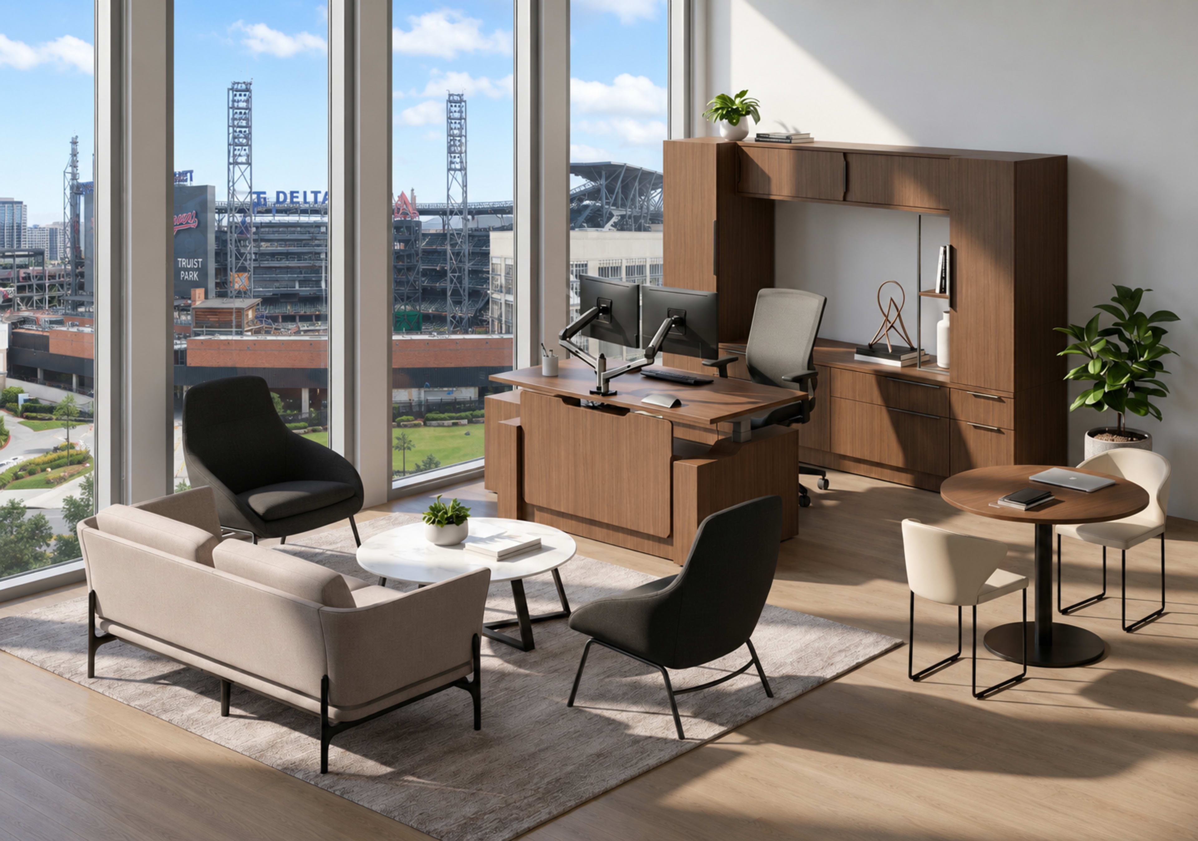The image shows a modern office space with large windows revealing a view of a stadium, featuring a desk, ergonomic chair, seating area with sofas and tables, and decorative plants.