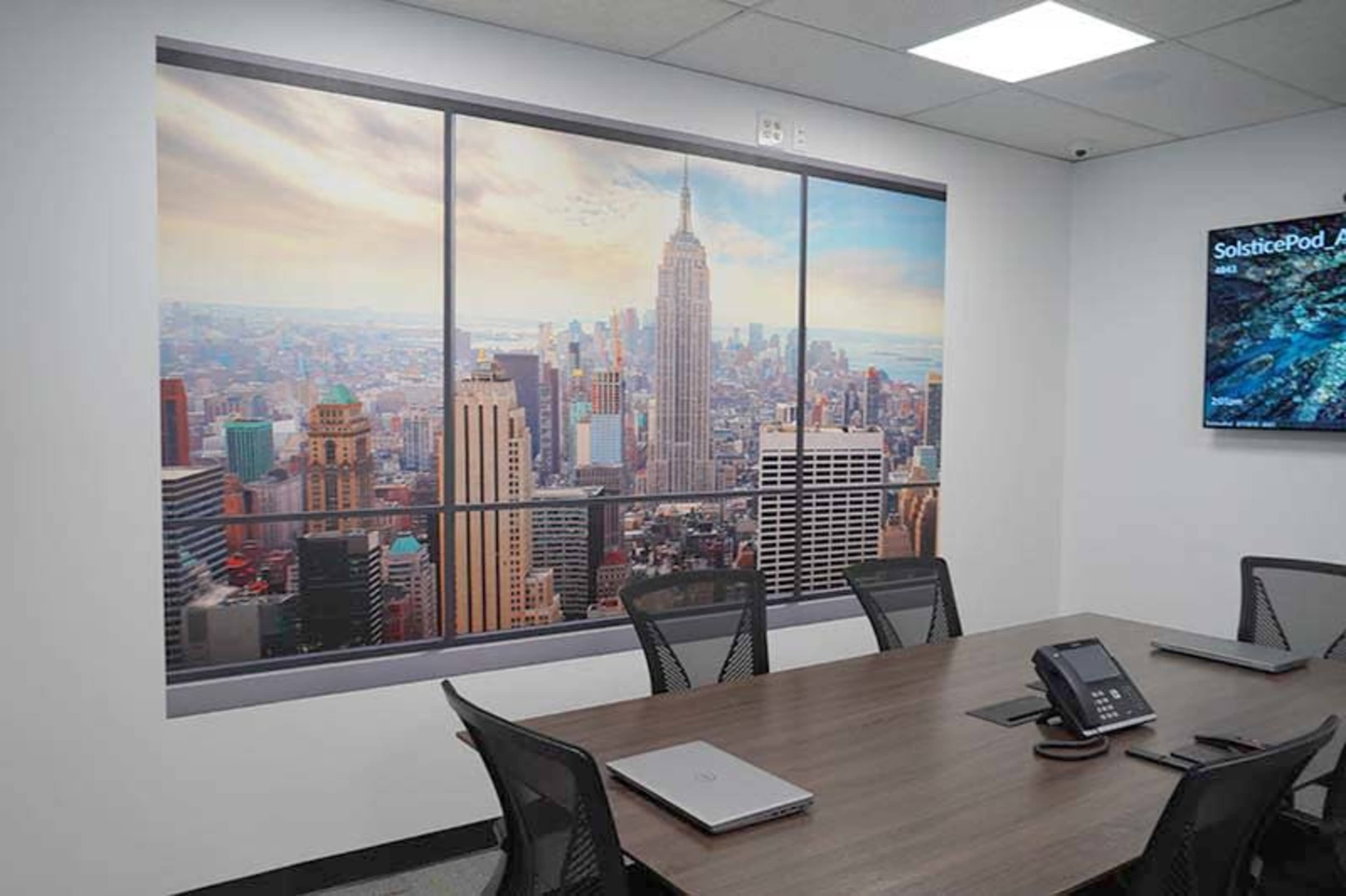 A conference room features a large wall mural depicting a panoramic view of the New York City skyline, including the Empire State Building.