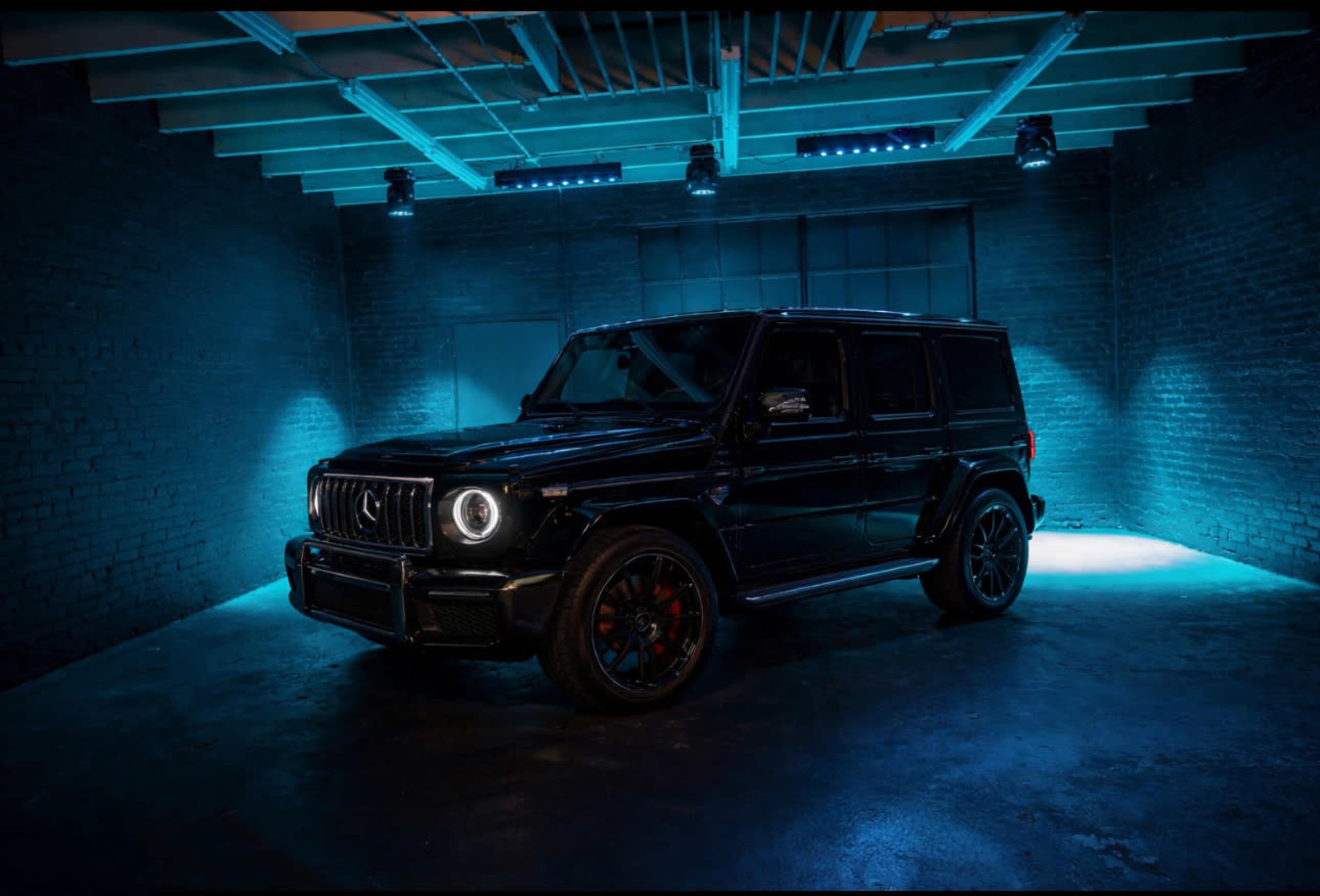 A black SUV is positioned in a dimly lit space with blue lighting illuminating the scene.