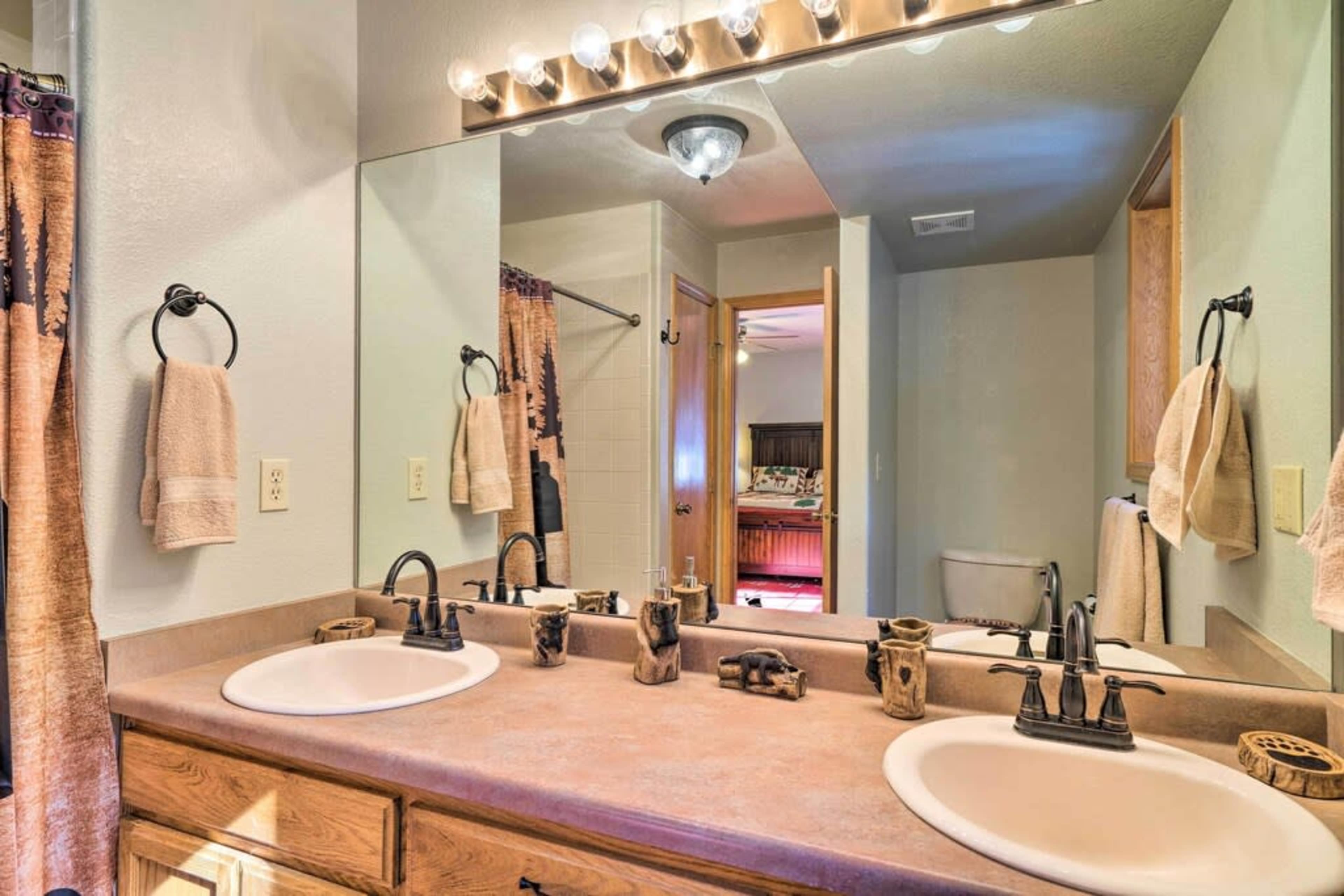 A bathroom features dual sinks, a large mirror, and wooden cabinetry, with towels and decorative items displayed on the counters.