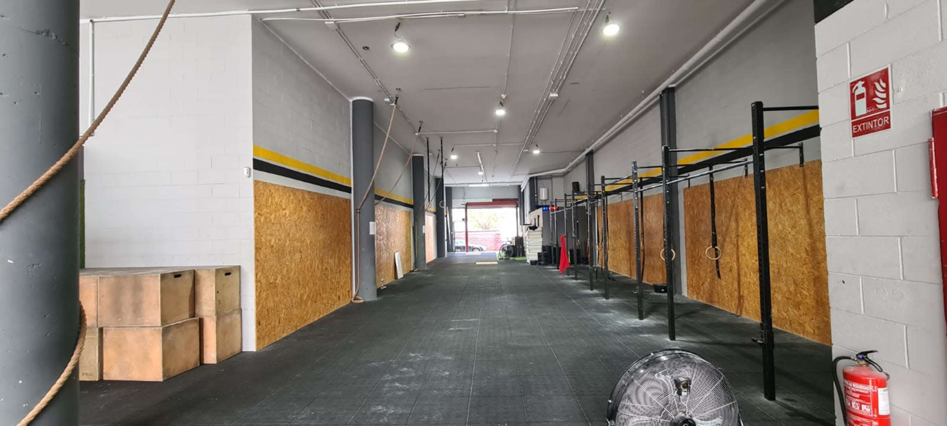 A spacious gym area with wooden box platforms on one side and a series of pull-up bars along the wall.