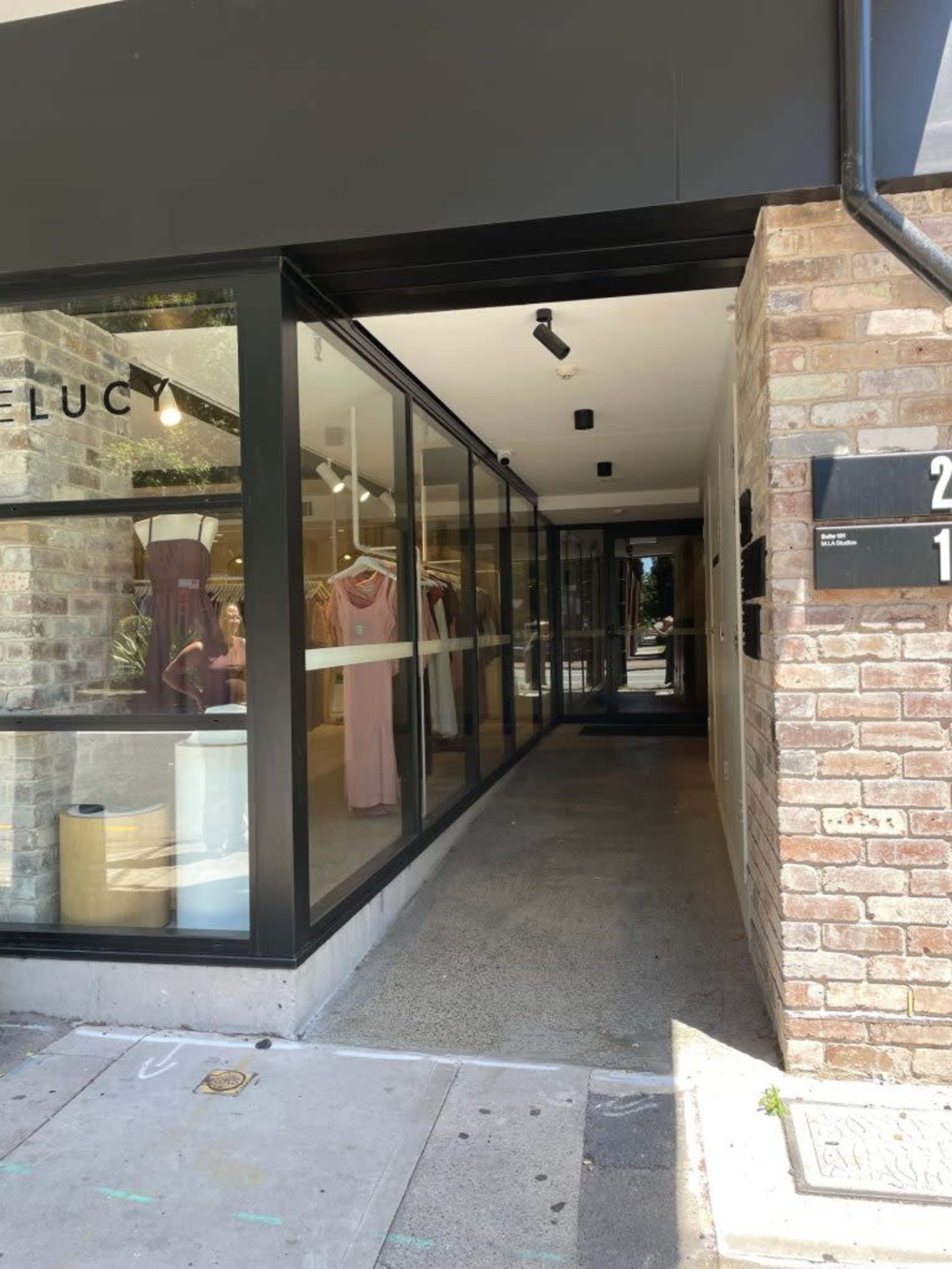 A storefront entrance with a glass facade leading into a clothing shop, featuring brick walls on either side.