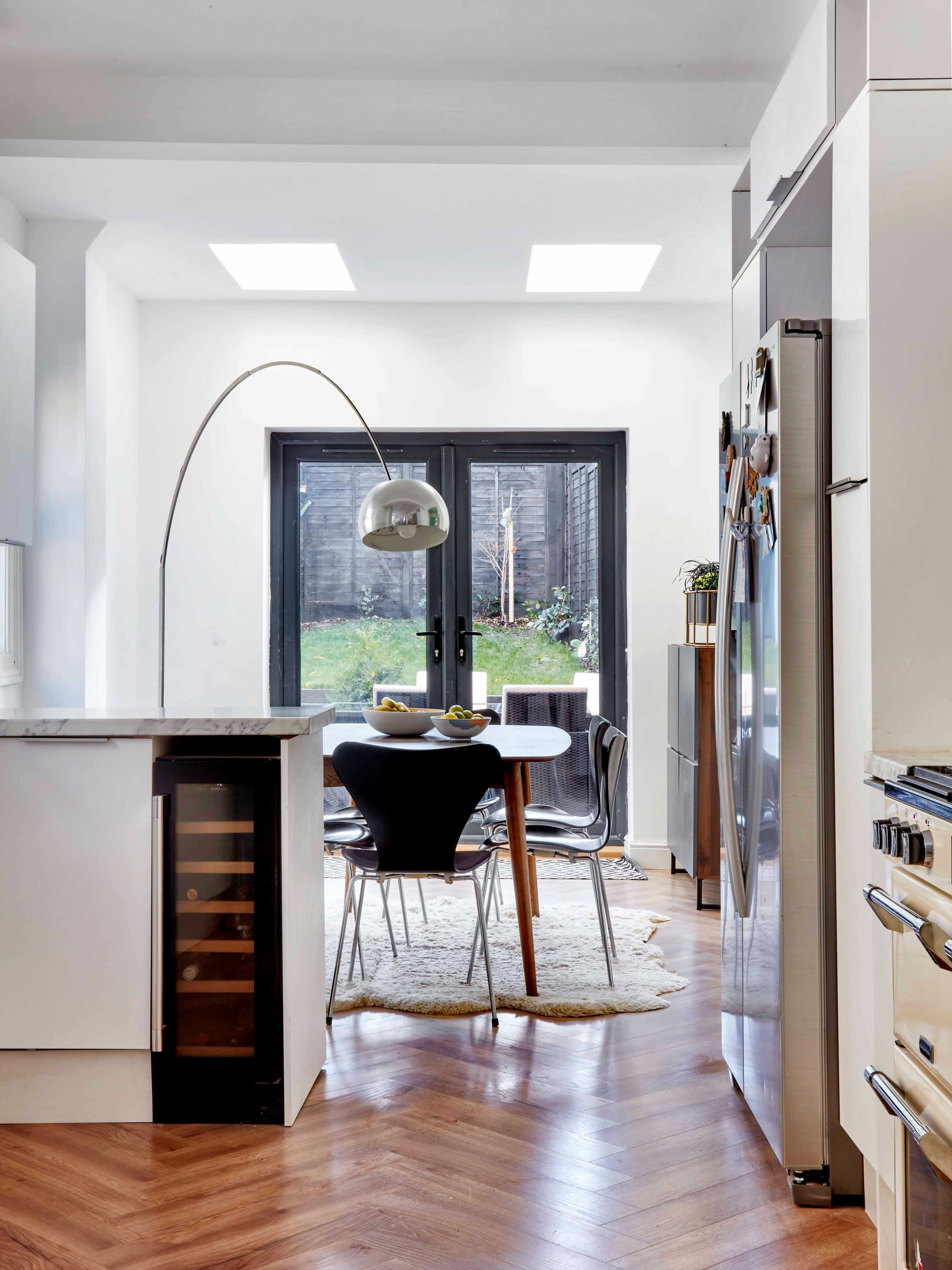 A modern kitchen with a sleek countertop, a dining area featuring a round table, and glass doors leading to an outdoor space.