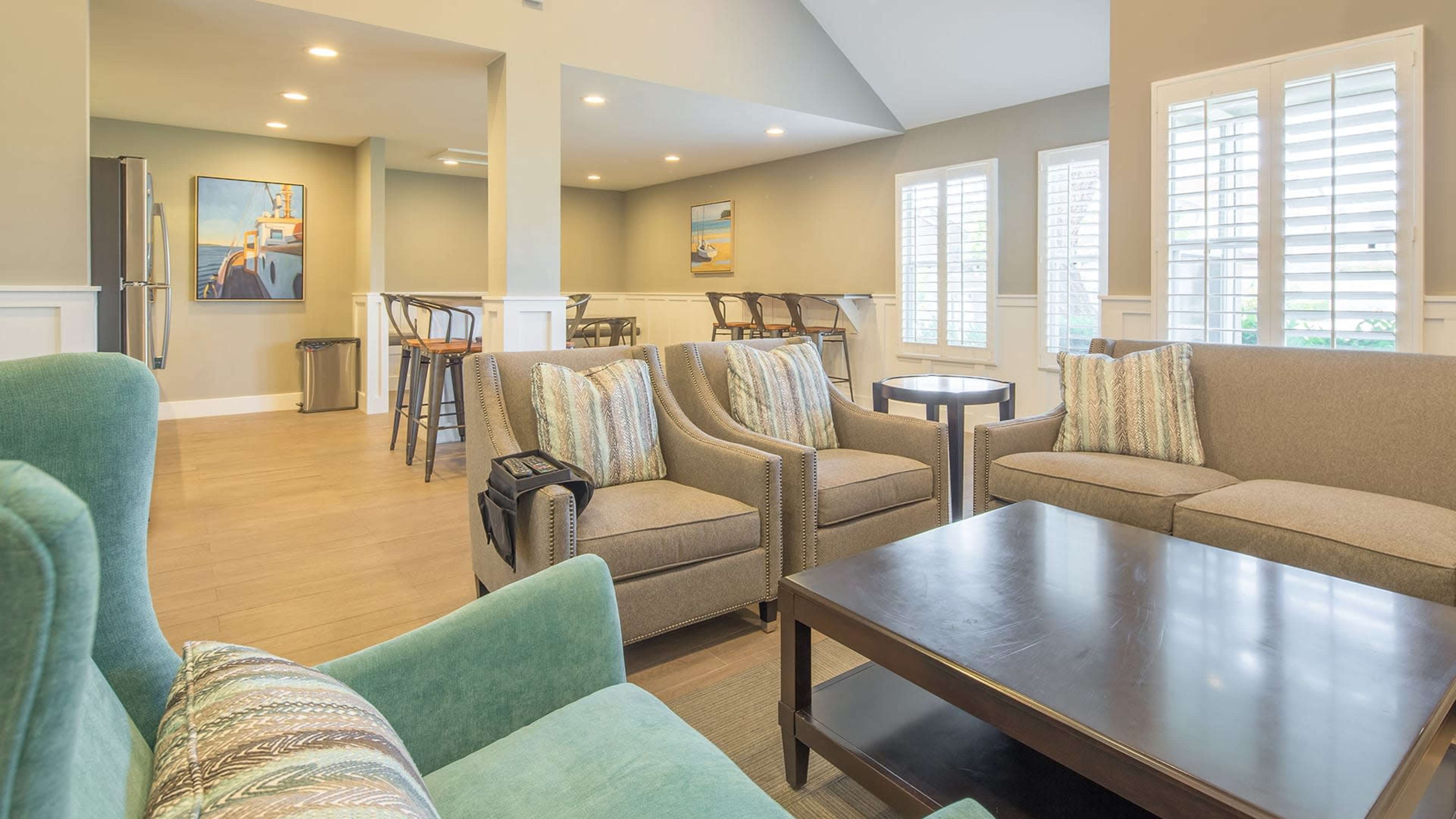 A cozy lounge area with gray sofas, a dark coffee table, and a bar-style seating arrangement in the background.
