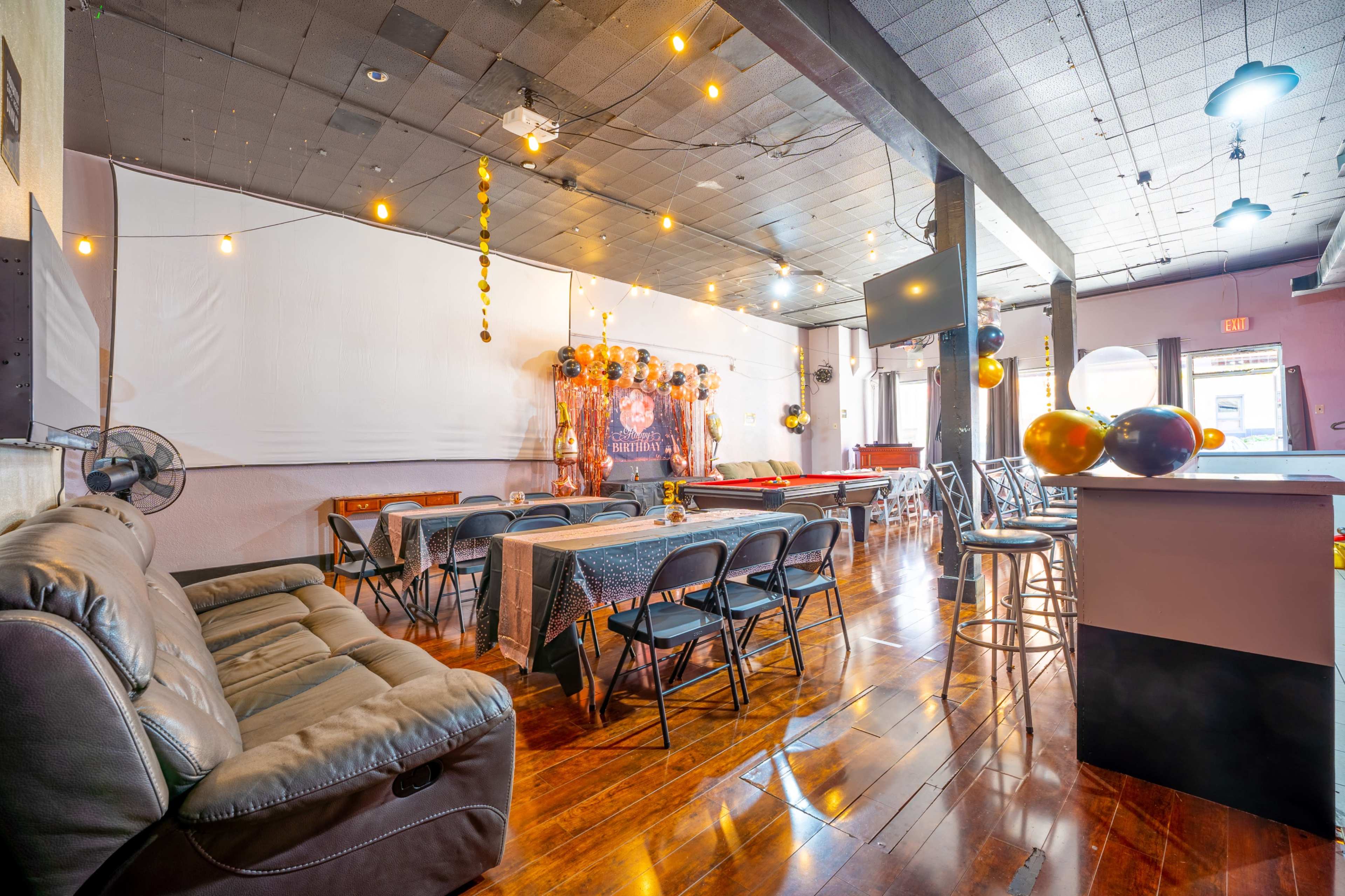 The interior of a spacious gathering room features seating arrangements, a pool table, and decorative lighting.