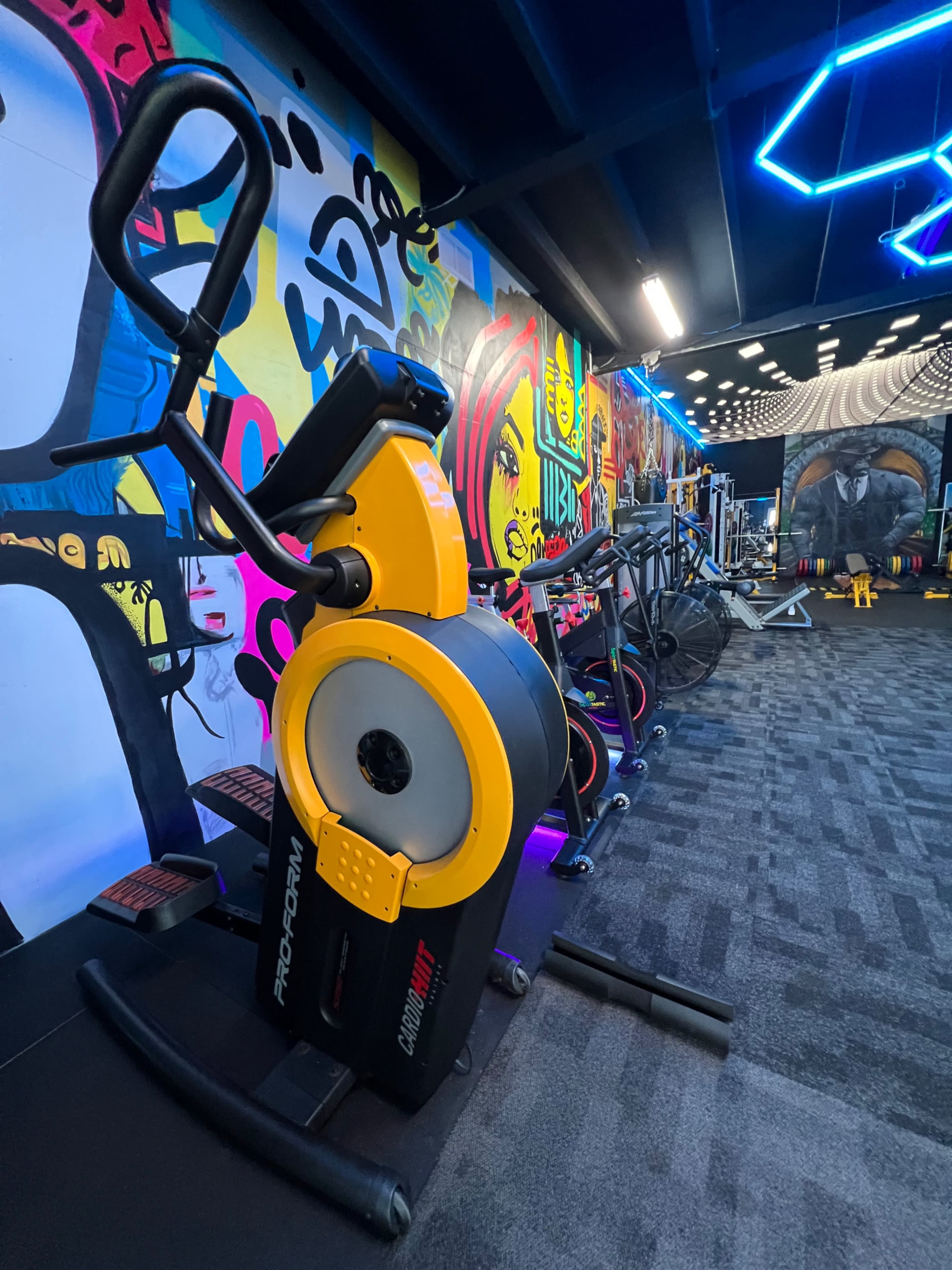 A stationary exercise bike is positioned in a gym adorned with colorful graffiti art on the walls.