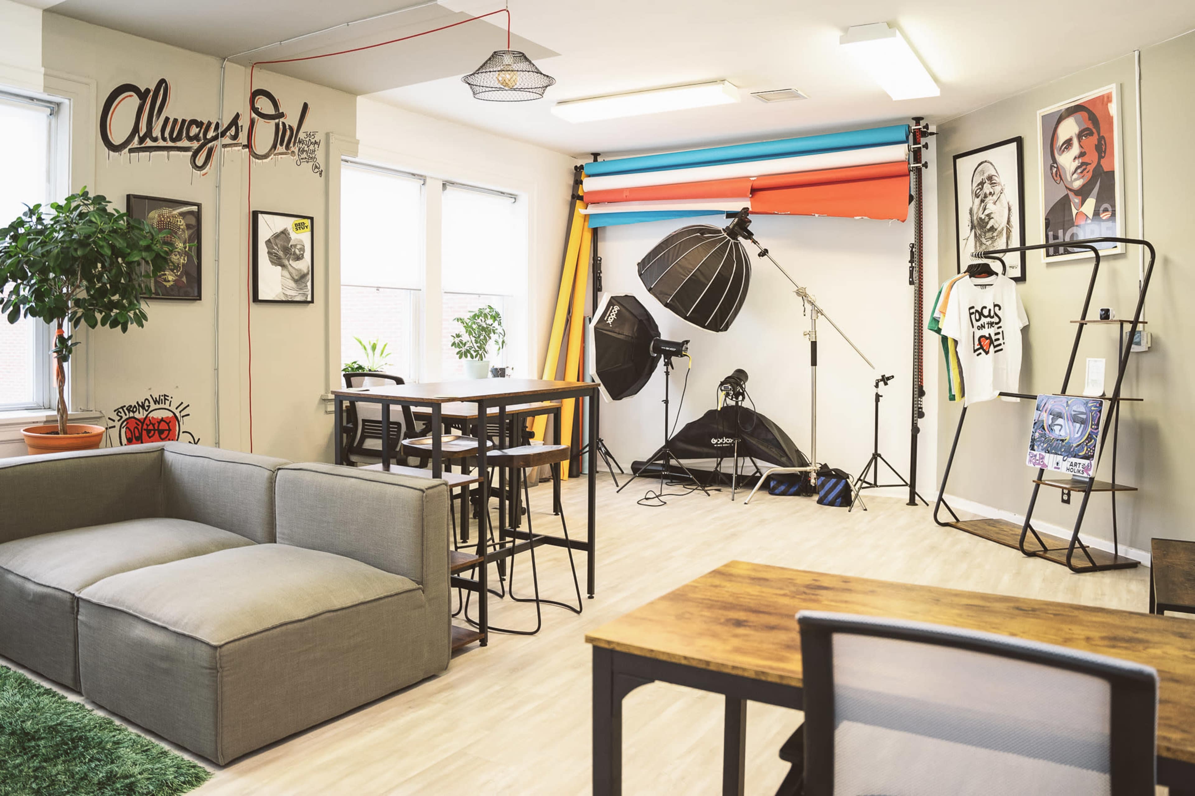 A creative studio space with a sofa, tables, photography equipment, and colorful backdrops.