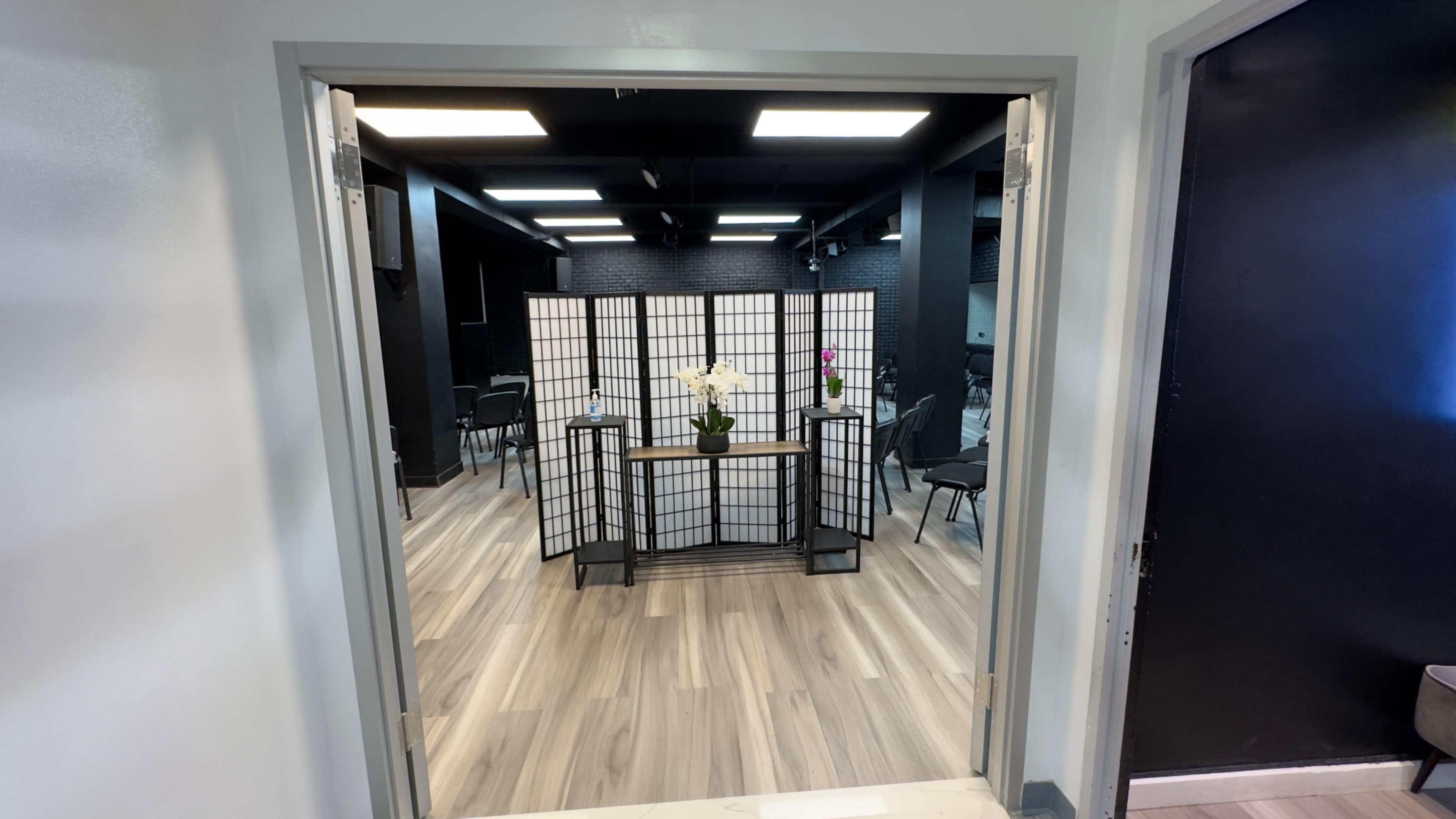 A reception area features a folding screen with a flower arrangement and several chairs arranged in a minimalist space.