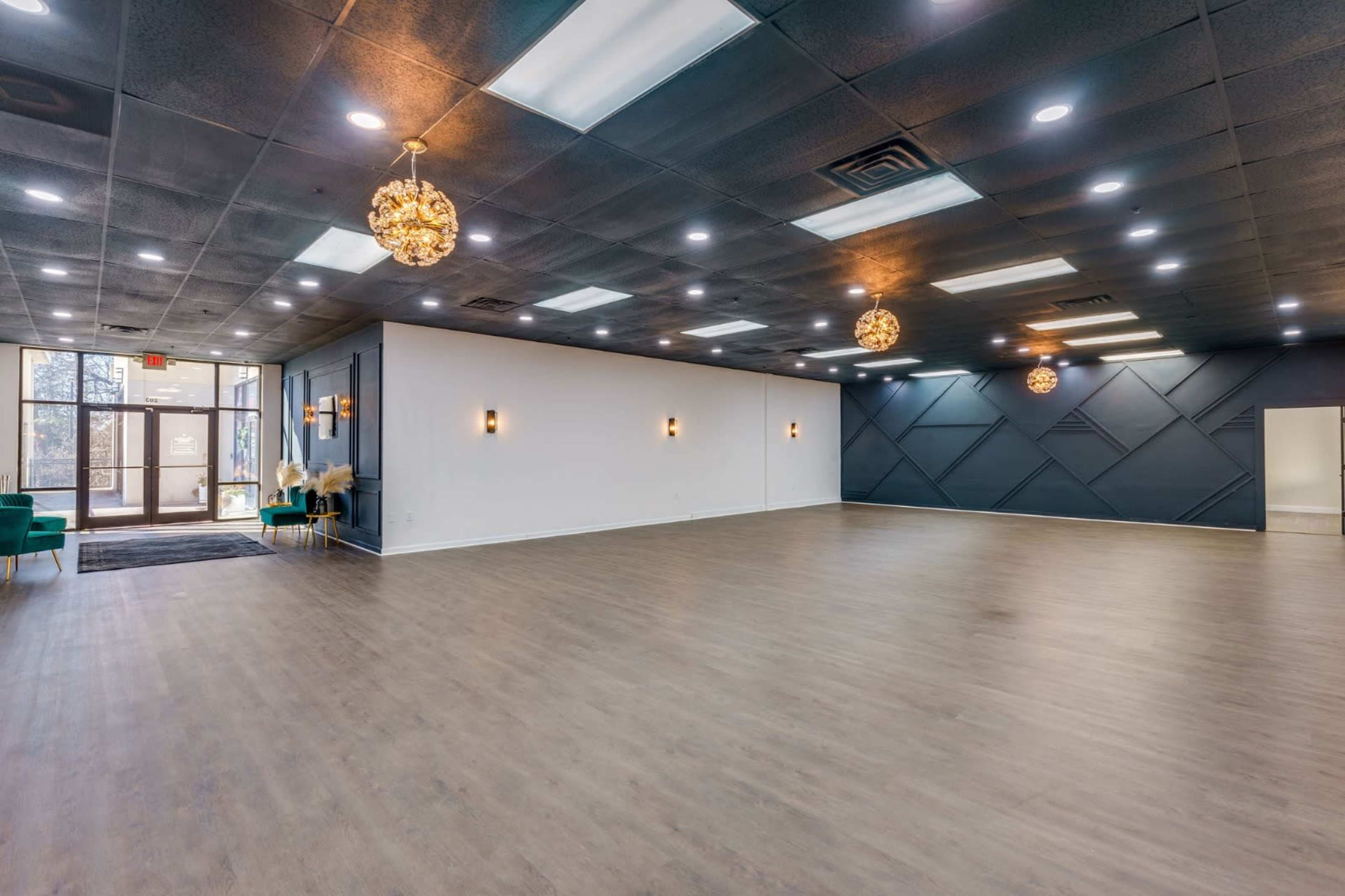 A spacious indoor venue with wooden flooring, high ceilings, and modern light fixtures.