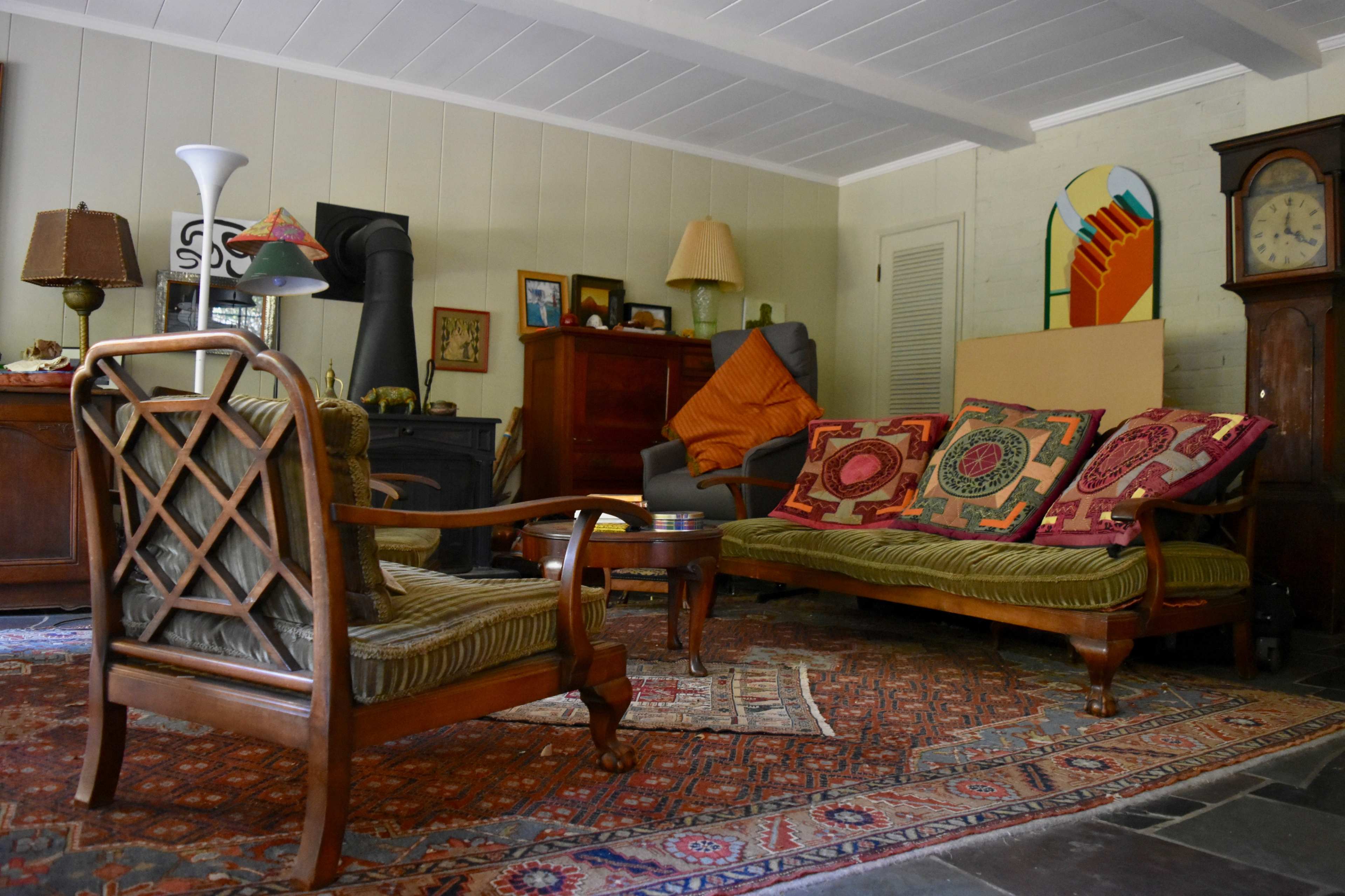 A cozy living room with antique furniture, a patterned rug, and a mix of decorative items on display.