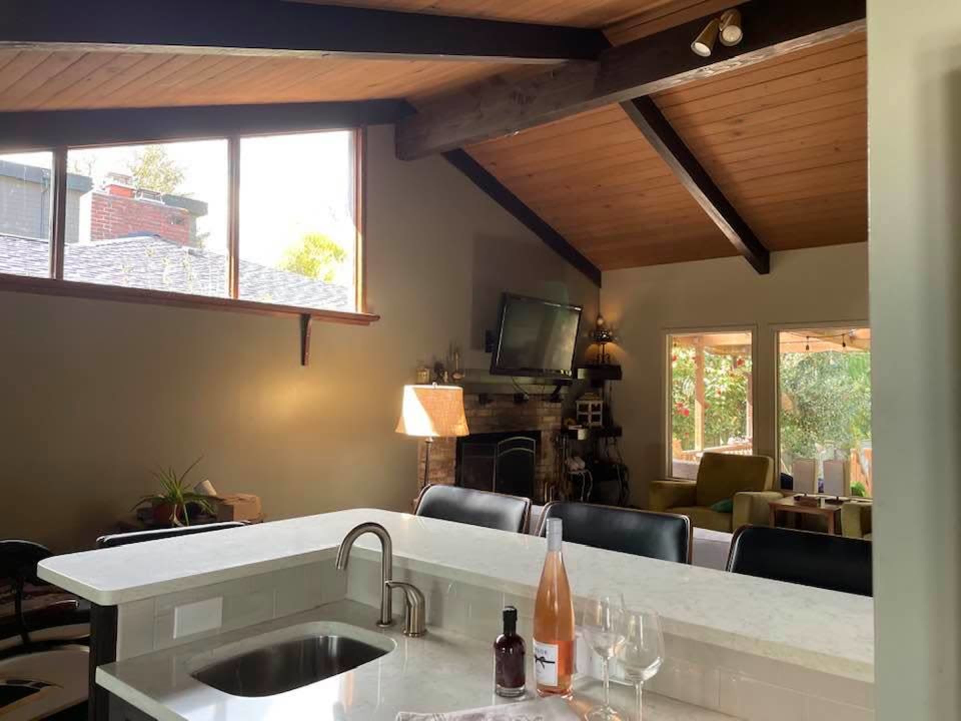 An open-concept living area with a kitchen bar, a stone fireplace, and large windows letting in natural light.