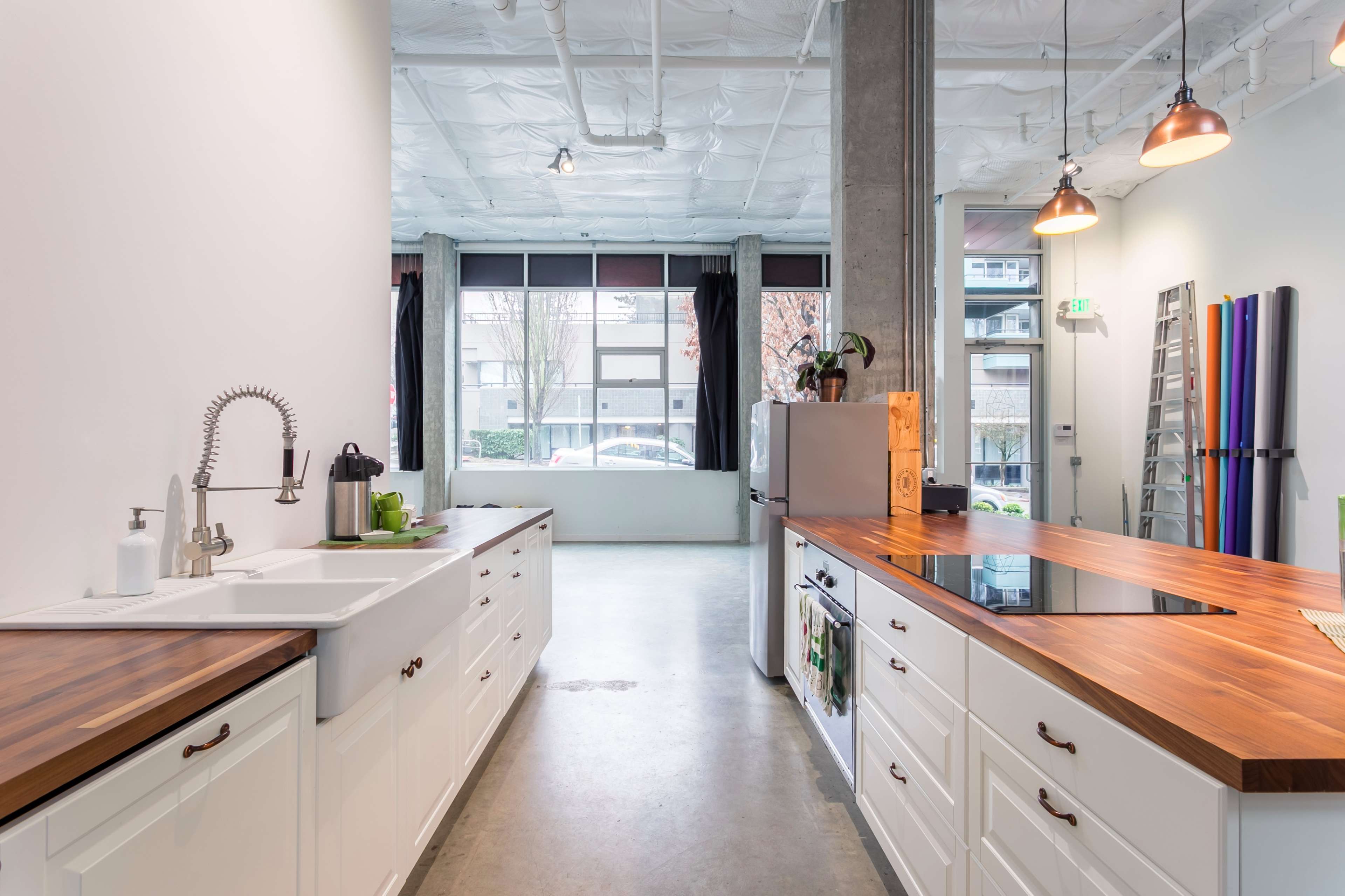 A modern kitchen featuring white cabinets, a wooden countertop, and a large window with natural light.