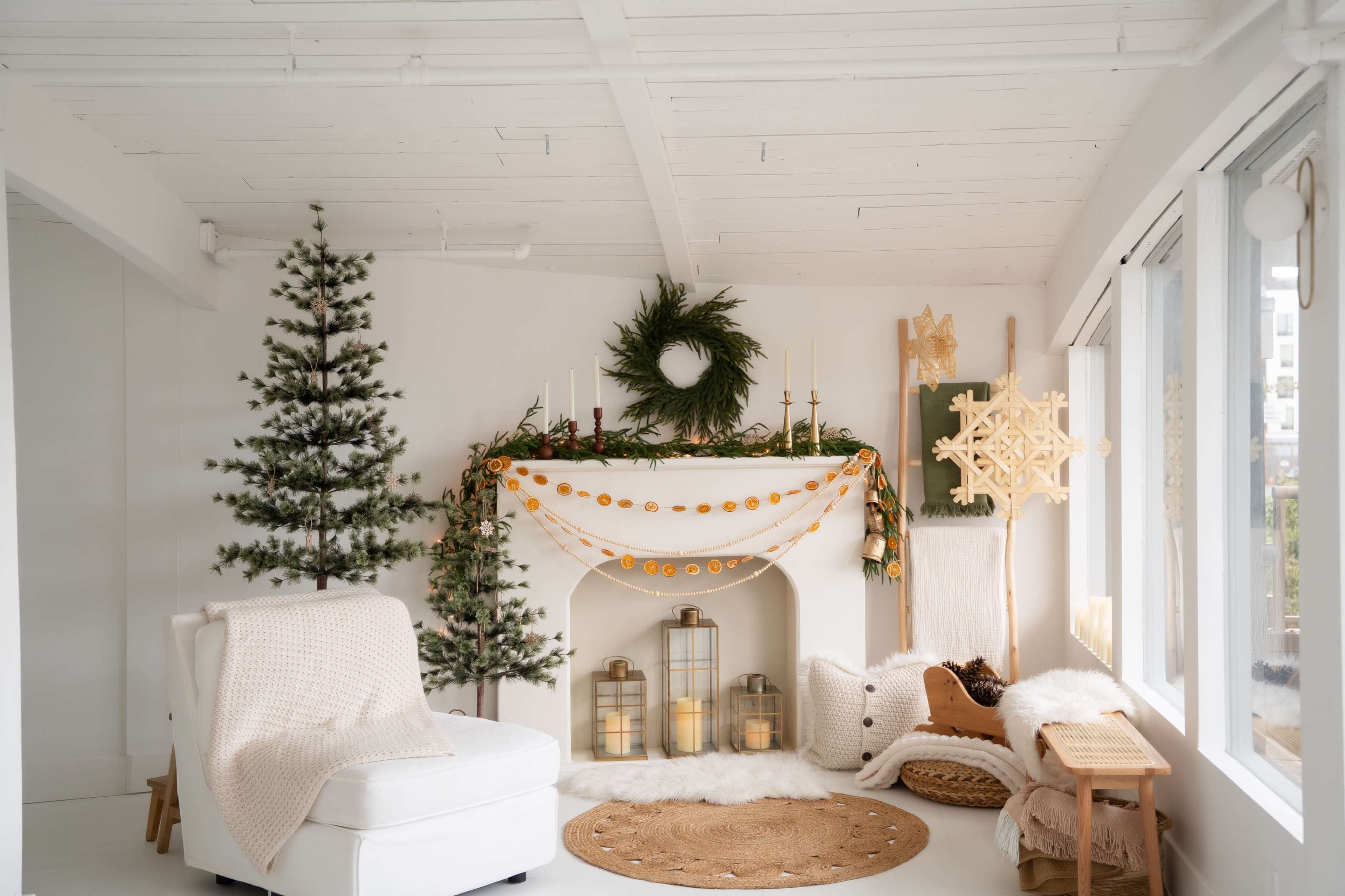 The cozy room features a white fireplace adorned with festive decorations, a Christmas tree, and a comfortable armchair.