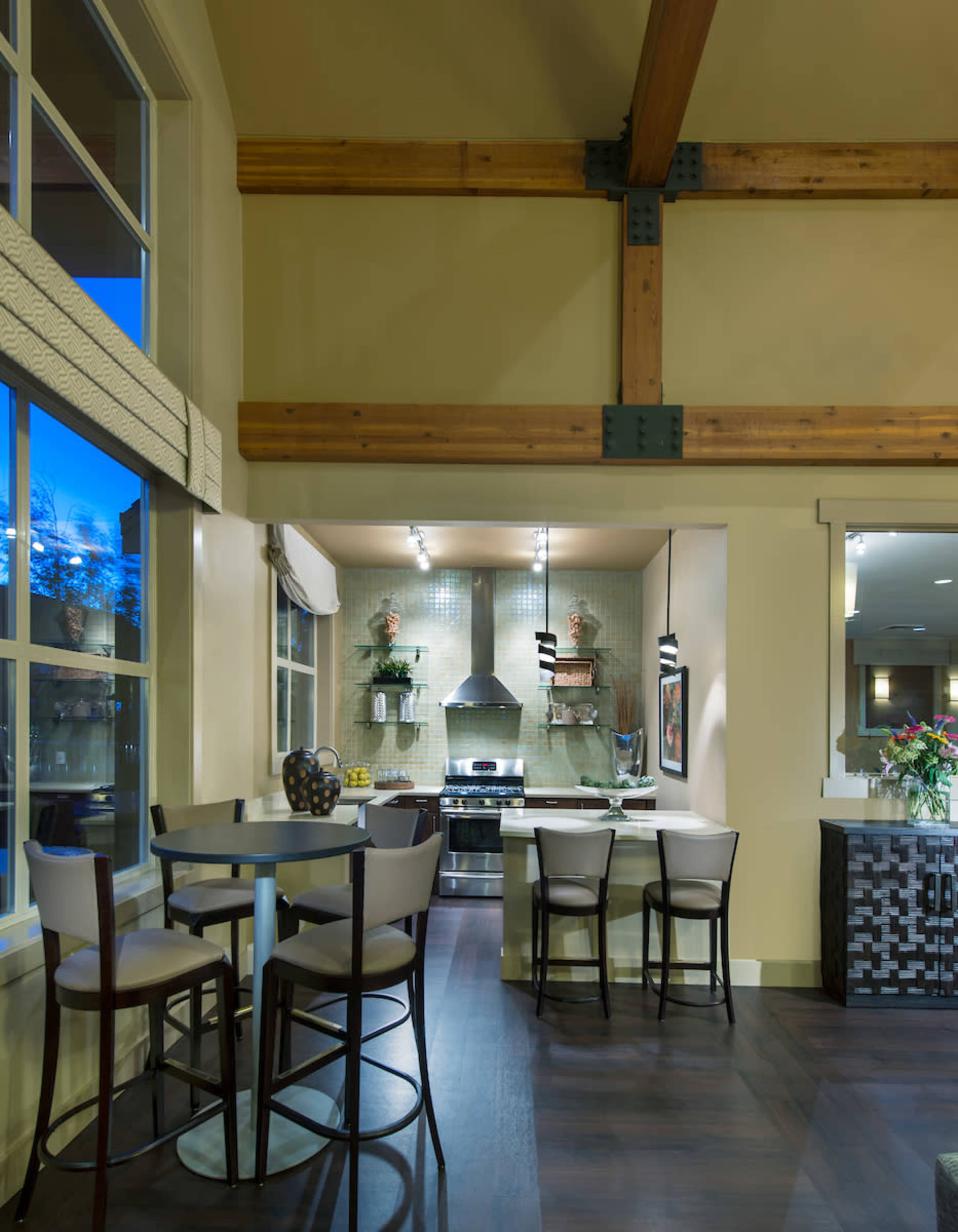 A modern kitchen area featuring a bar table with stools, a stove, and decorative elements on the walls.
