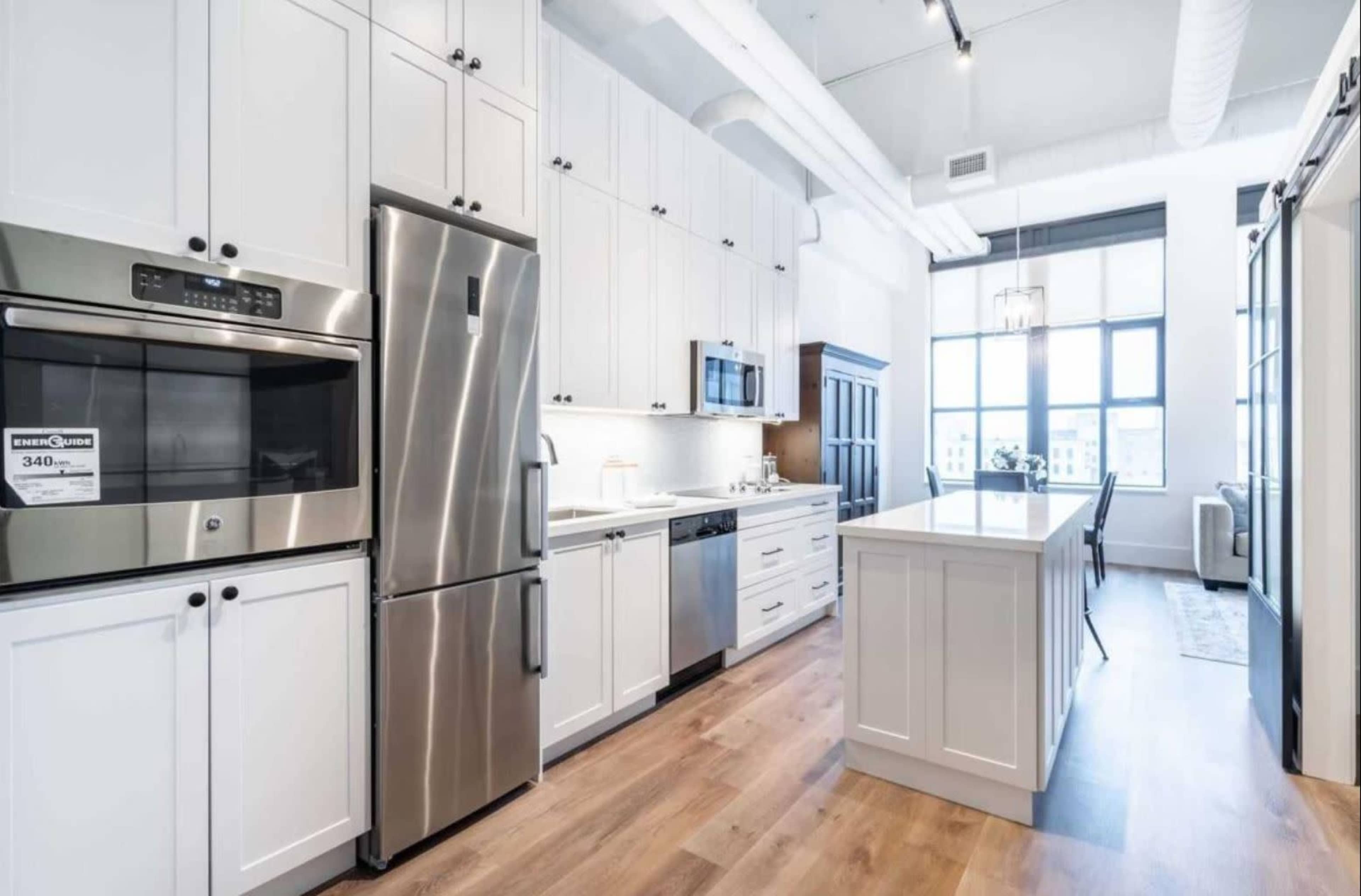 A modern kitchen with white cabinets, stainless steel appliances, and a central island with a light wood countertop.