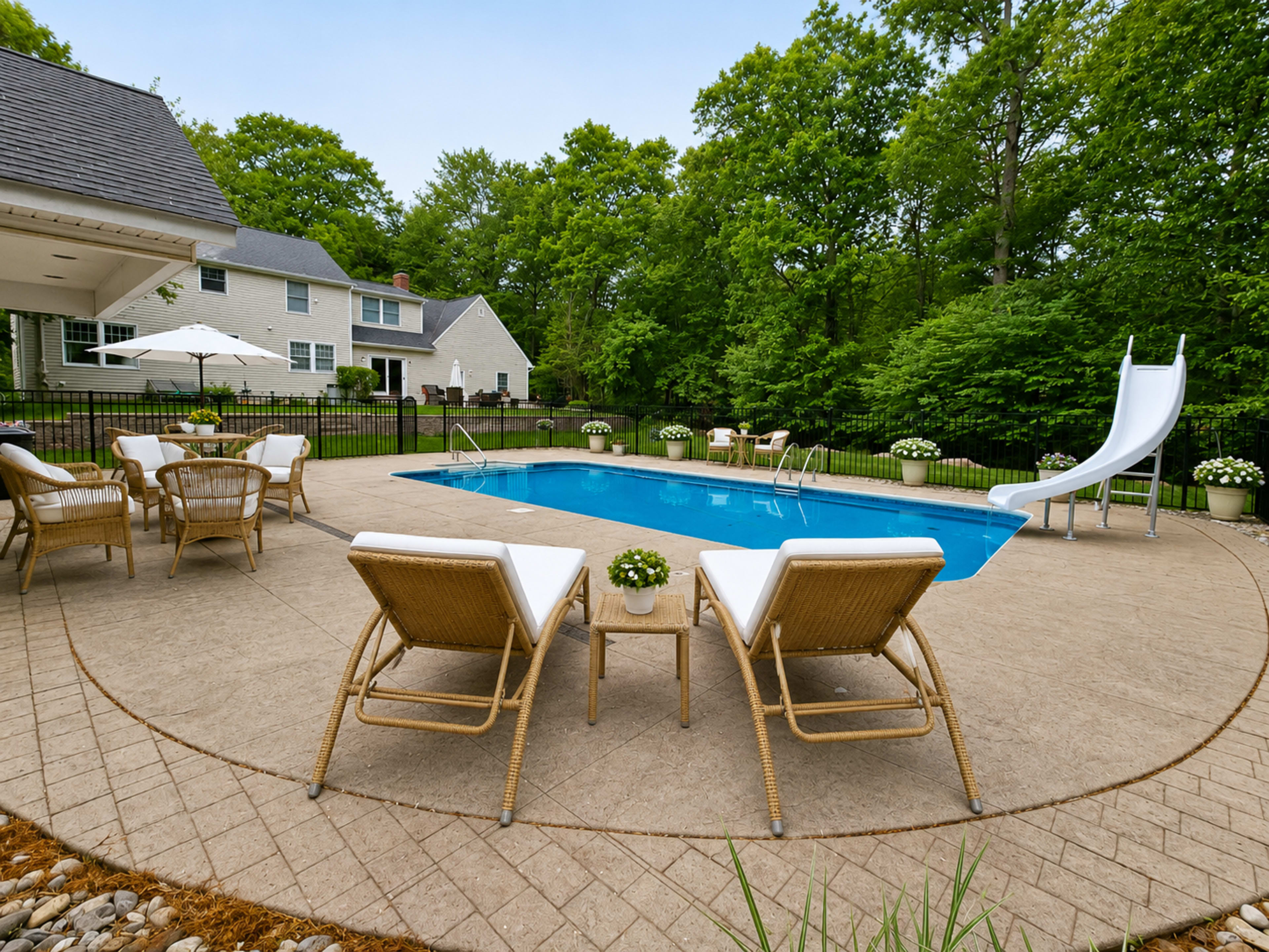 The image shows a backyard with a swimming pool surrounded by lounge chairs, a slide, and lush greenery.