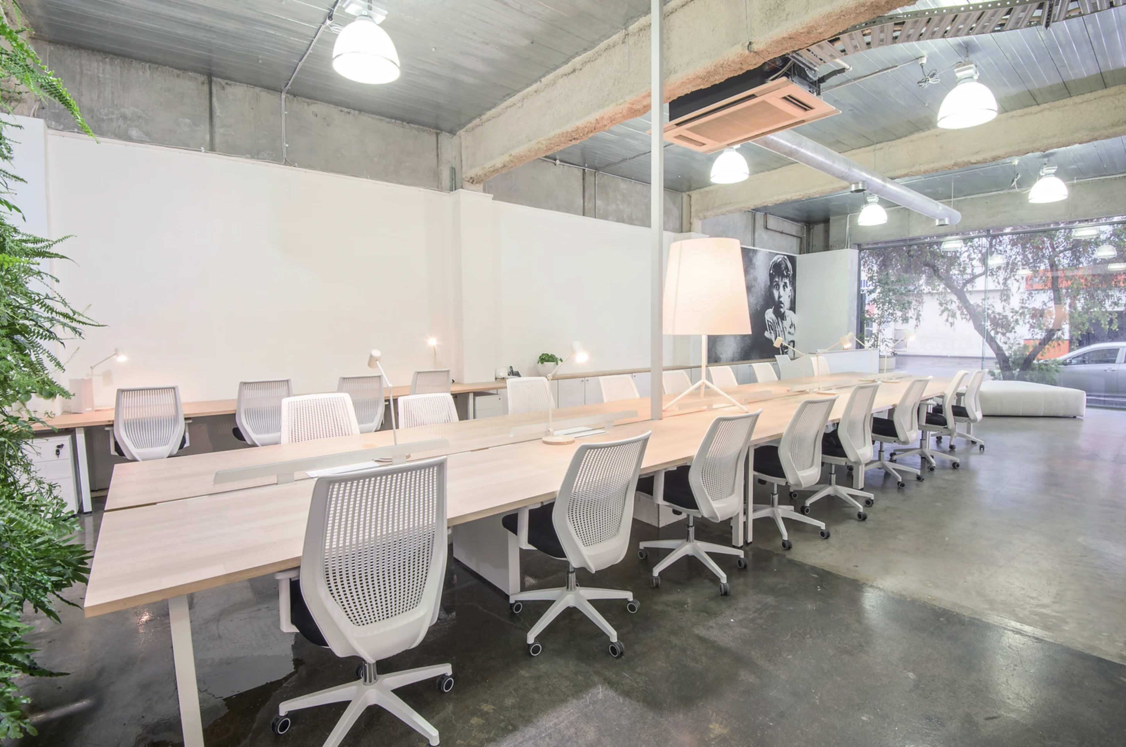 A modern office space with multiple white desks and ergonomic chairs arranged in a bright, open layout.