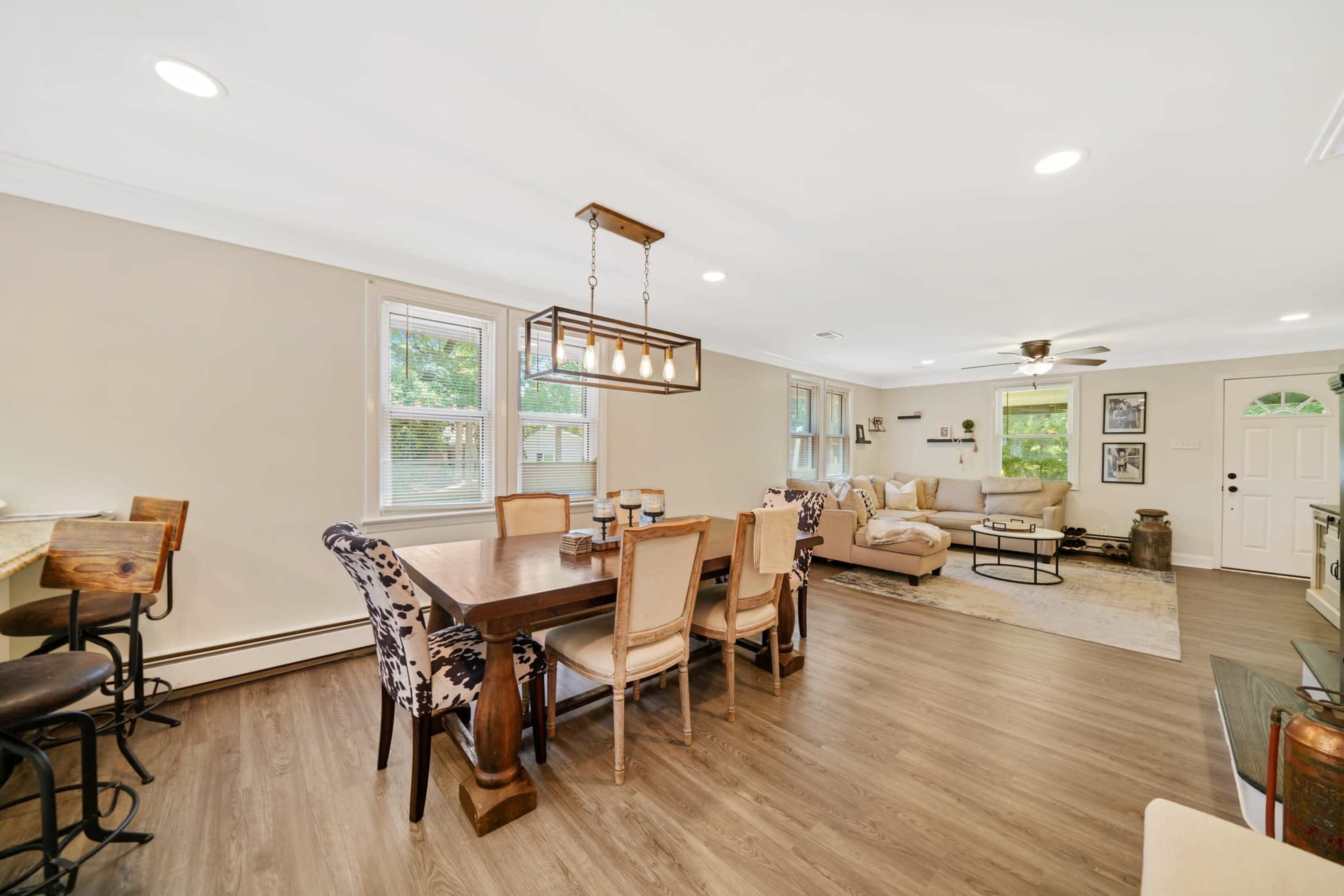 An open-concept living and dining area with a wooden dining table, chairs, and a seating arrangement in a well-lit space.