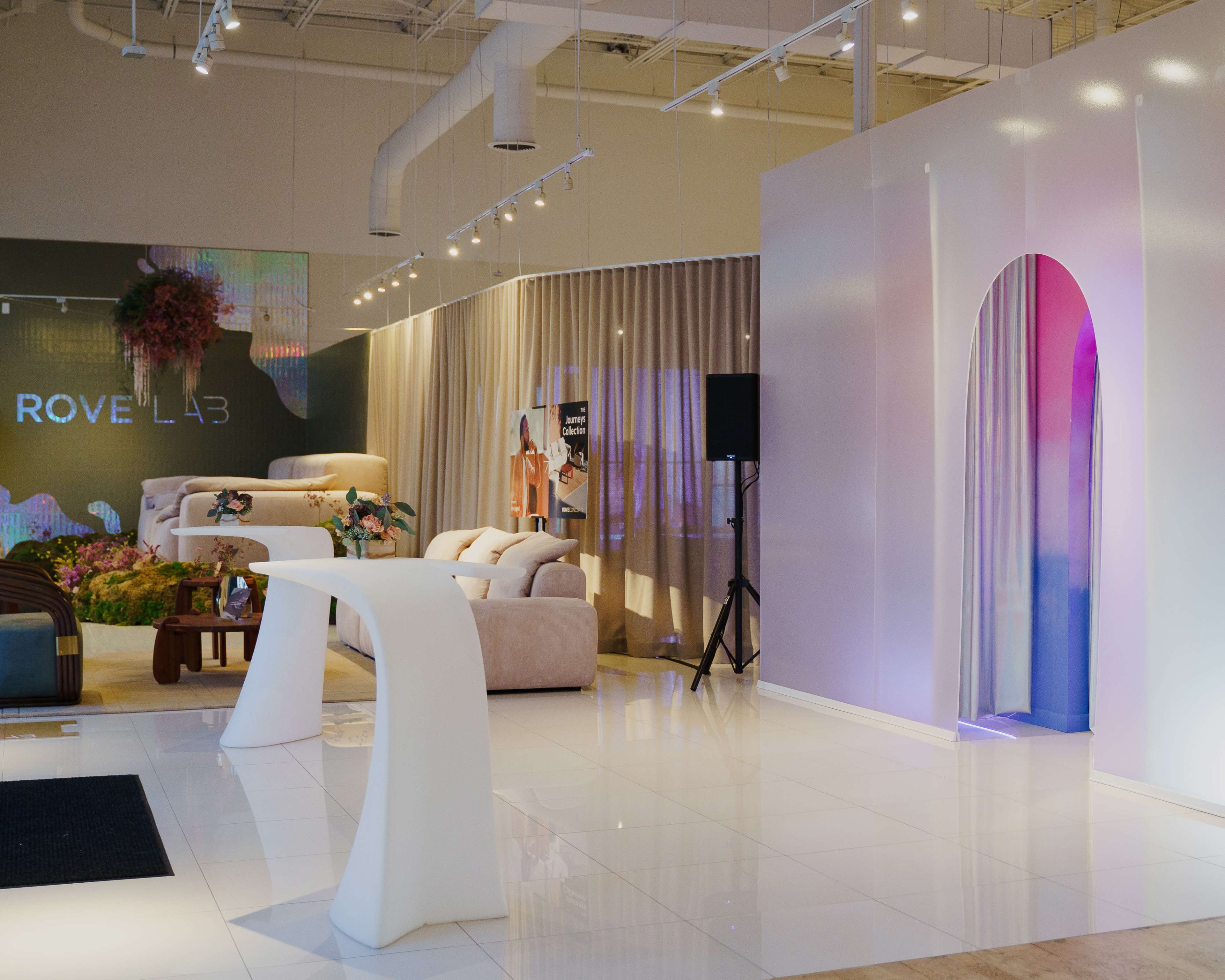 The image shows a modern interior space with sleek furniture, large curtains, and a minimalist white archway under soft lighting.