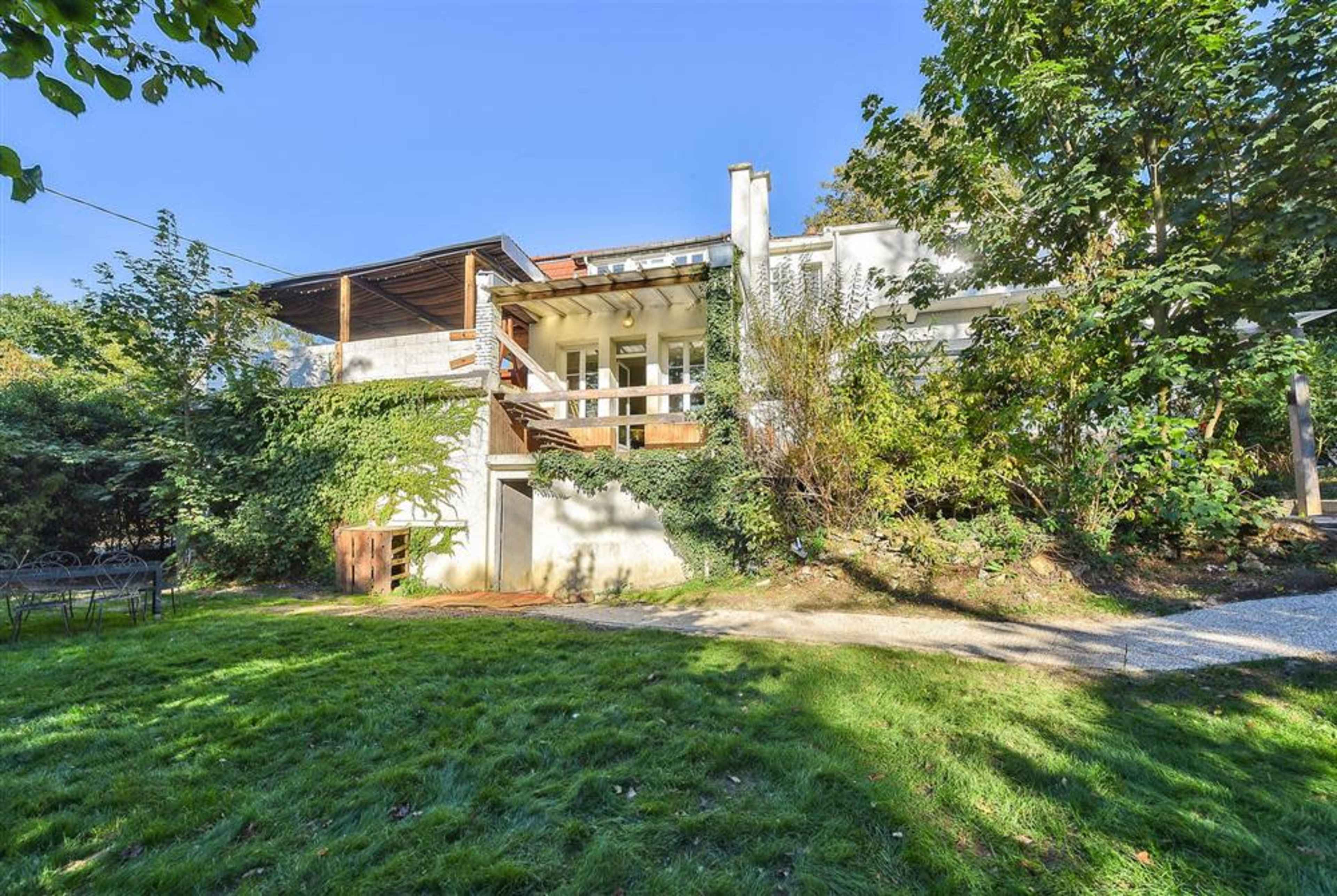 A modern two-story house surrounded by greenery and a well-maintained lawn.