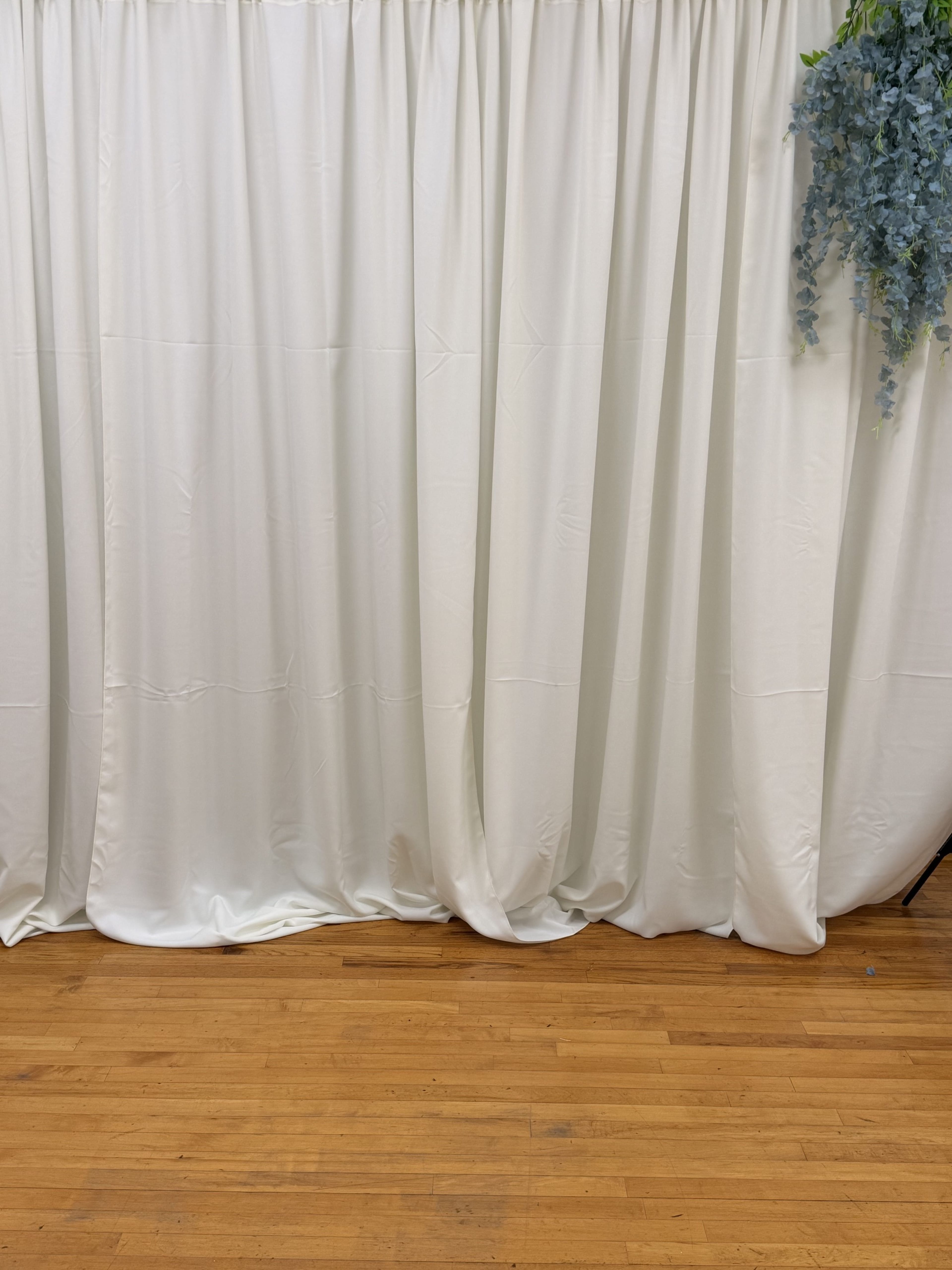 The image features a white fabric curtain draped against a wooden floor.
