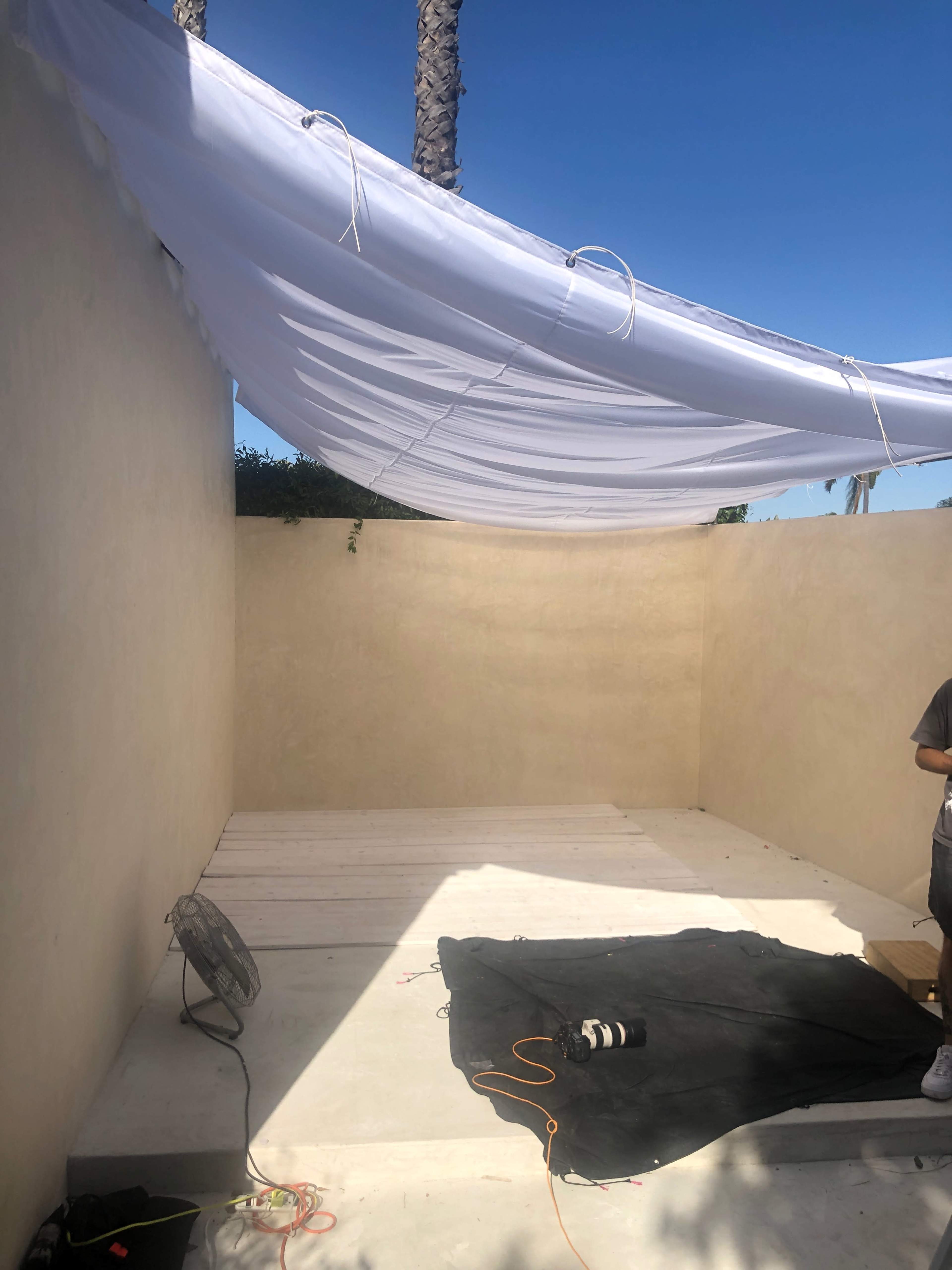 A partially completed interior space features a white canopy hanging from the ceiling and a black cloth on the floor.