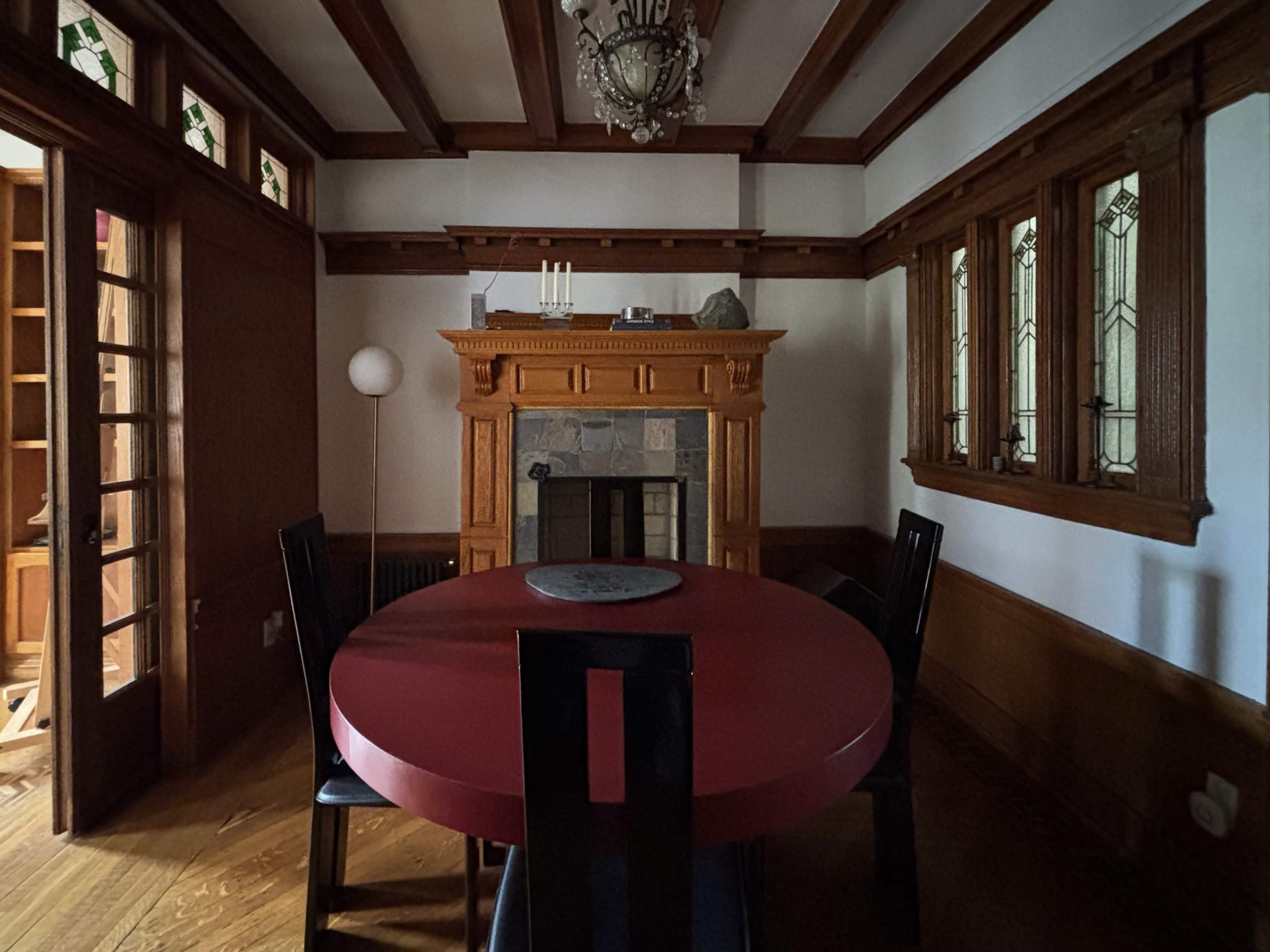 A round red table sits in a dimly lit dining room with wood-paneled walls and a decorative fireplace.