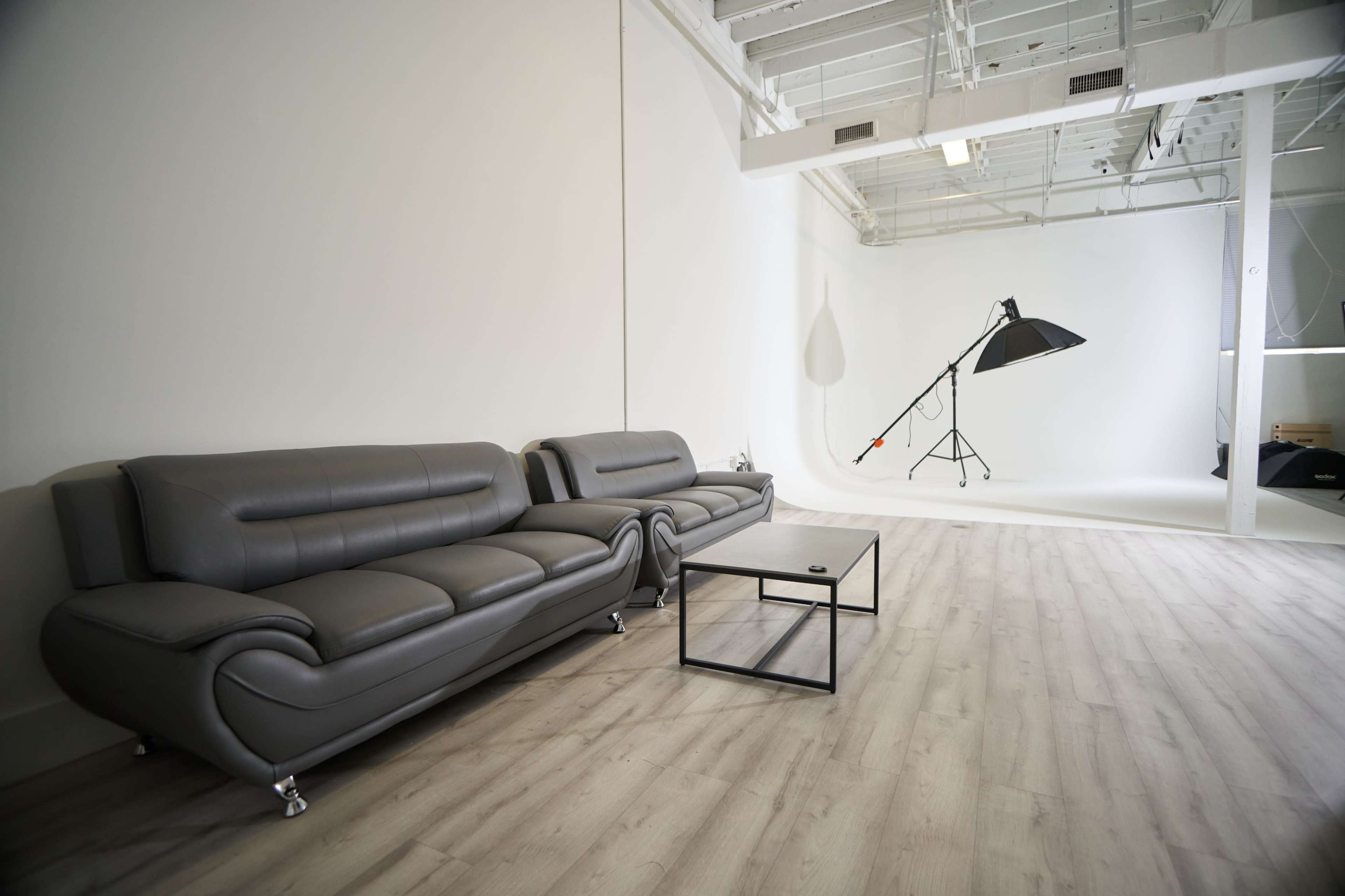 A modern interior space featuring two gray sofas and a black coffee table, with a large lighting setup in the background.