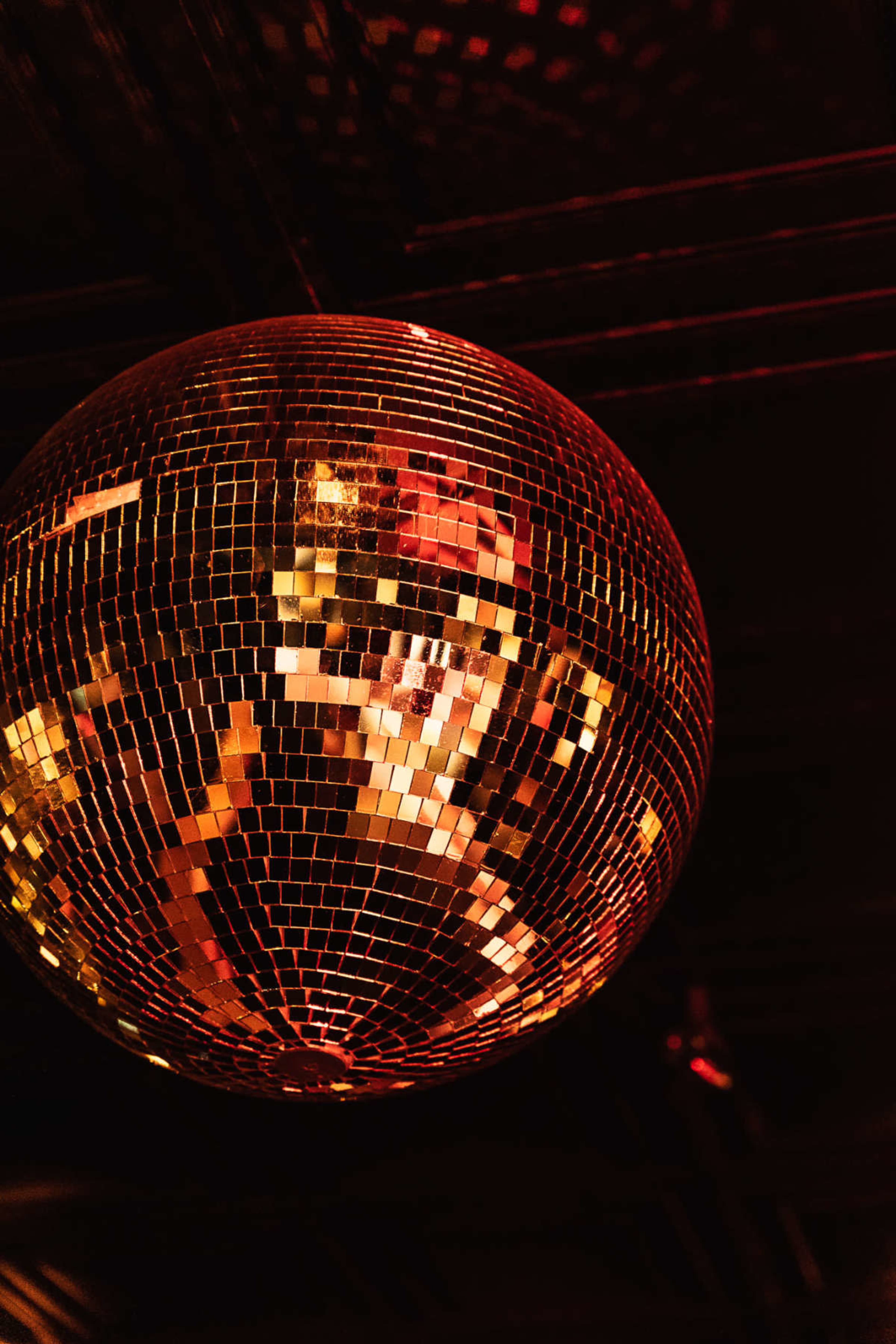A disco ball hangs from the ceiling, reflecting colorful lights in a dimly lit room.