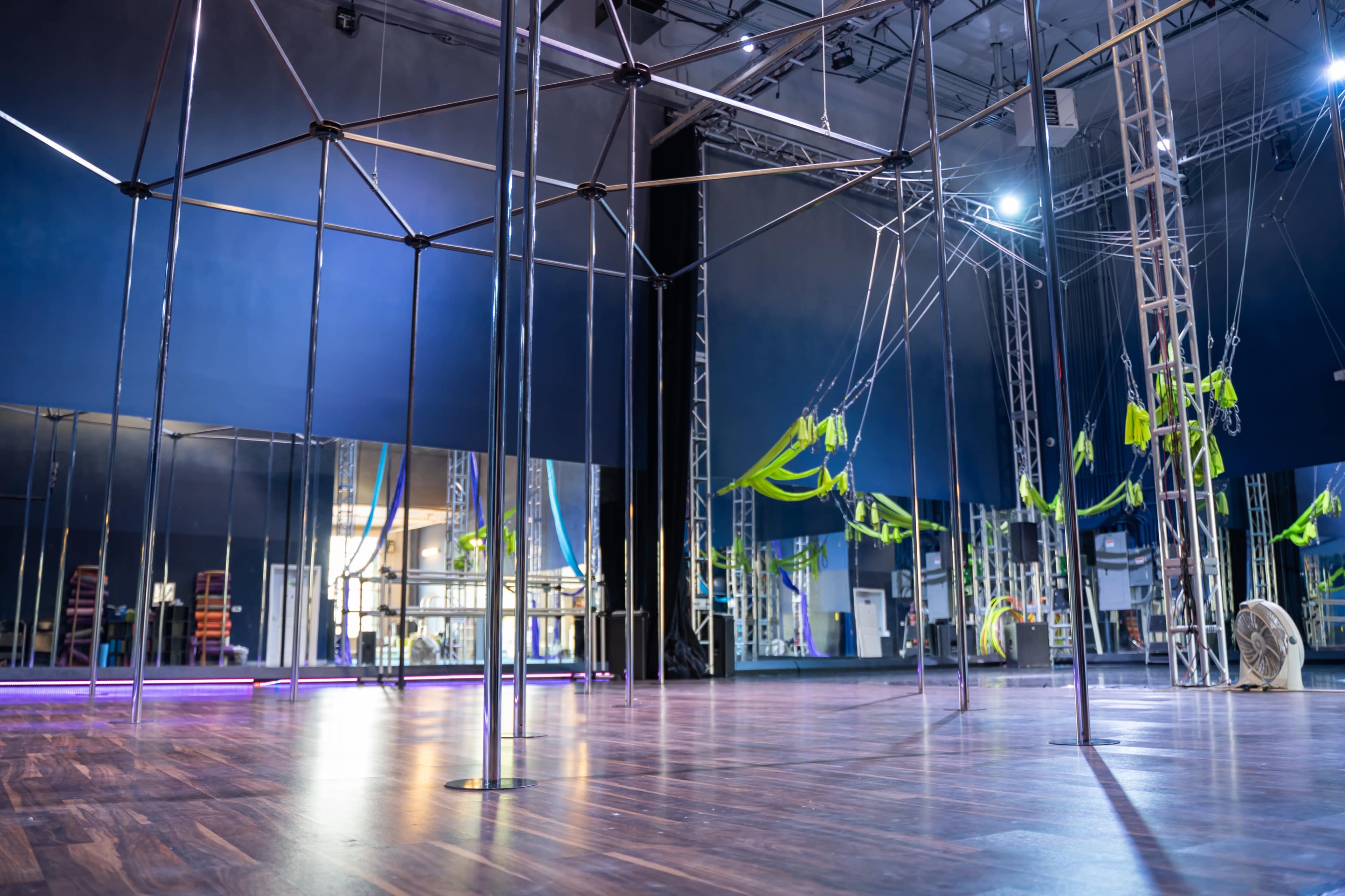 An indoor fitness studio equipped with a framework for aerial exercises and mirrors lining the walls.