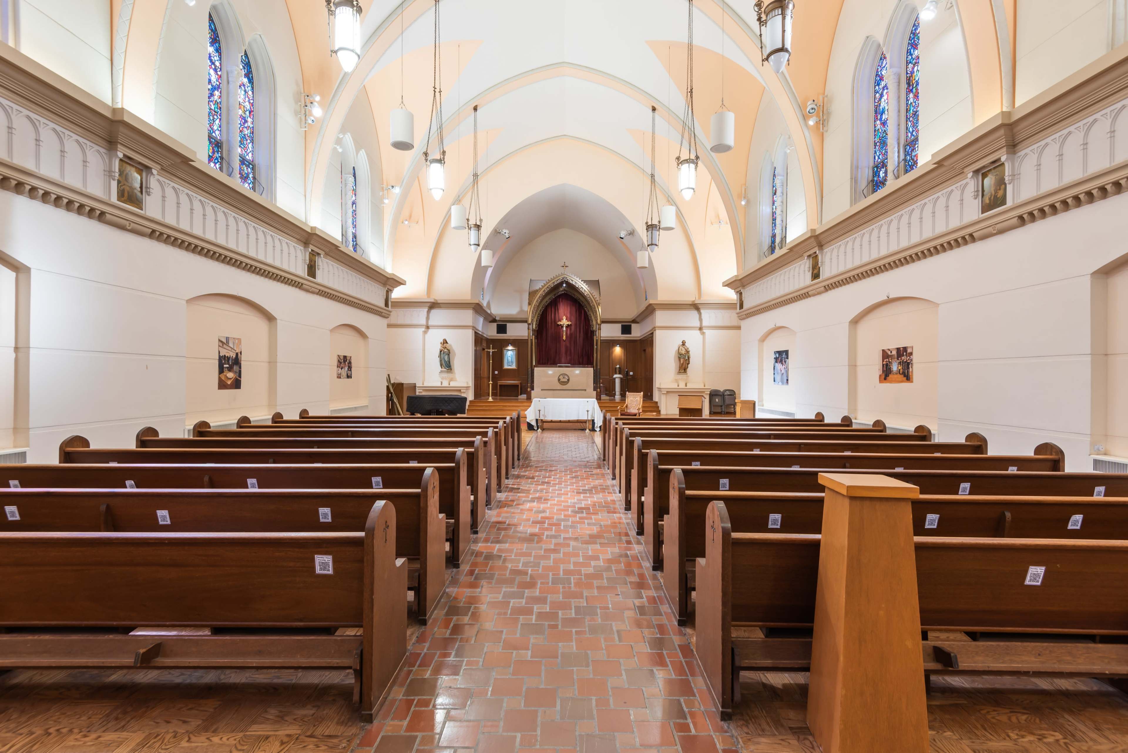 The image shows the interior of a church with wooden pews arranged in rows facing an altar at the rear.