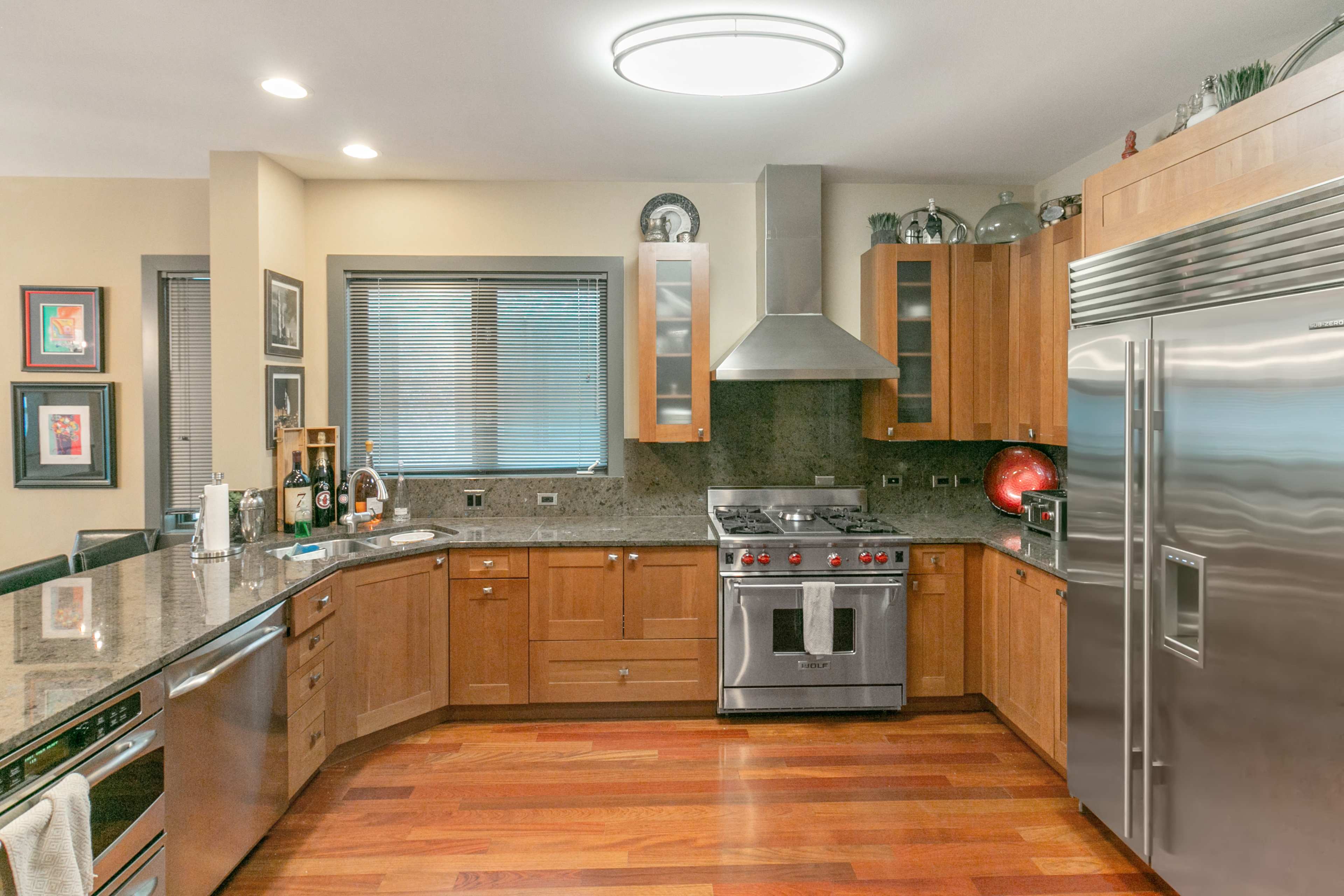 A modern kitchen features wooden cabinets, stainless steel appliances, and a granite countertop.
