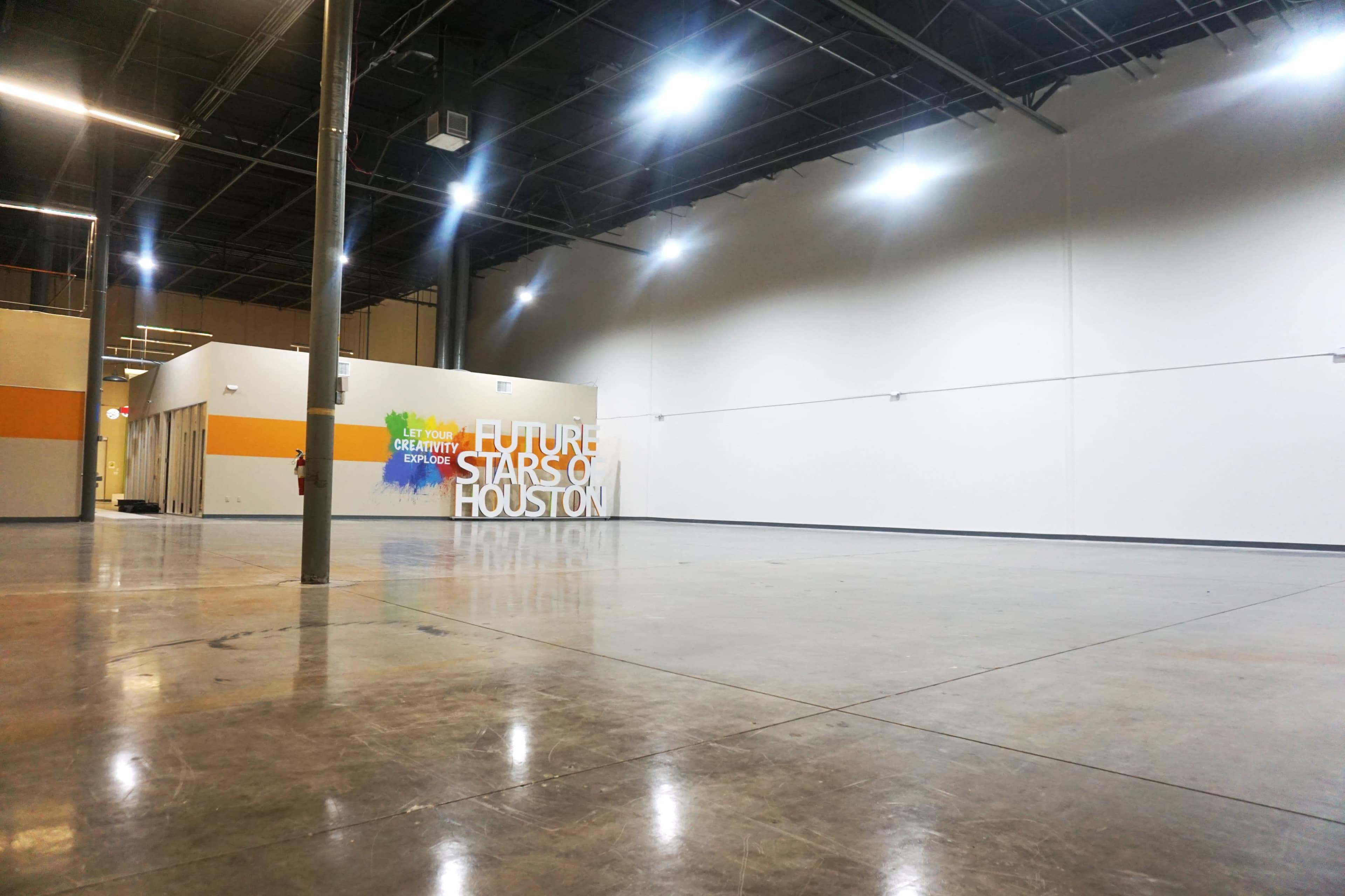 A spacious, empty indoor area with a polished concrete floor and a wall featuring the words "FUTURE STARS OF HOUSTON."