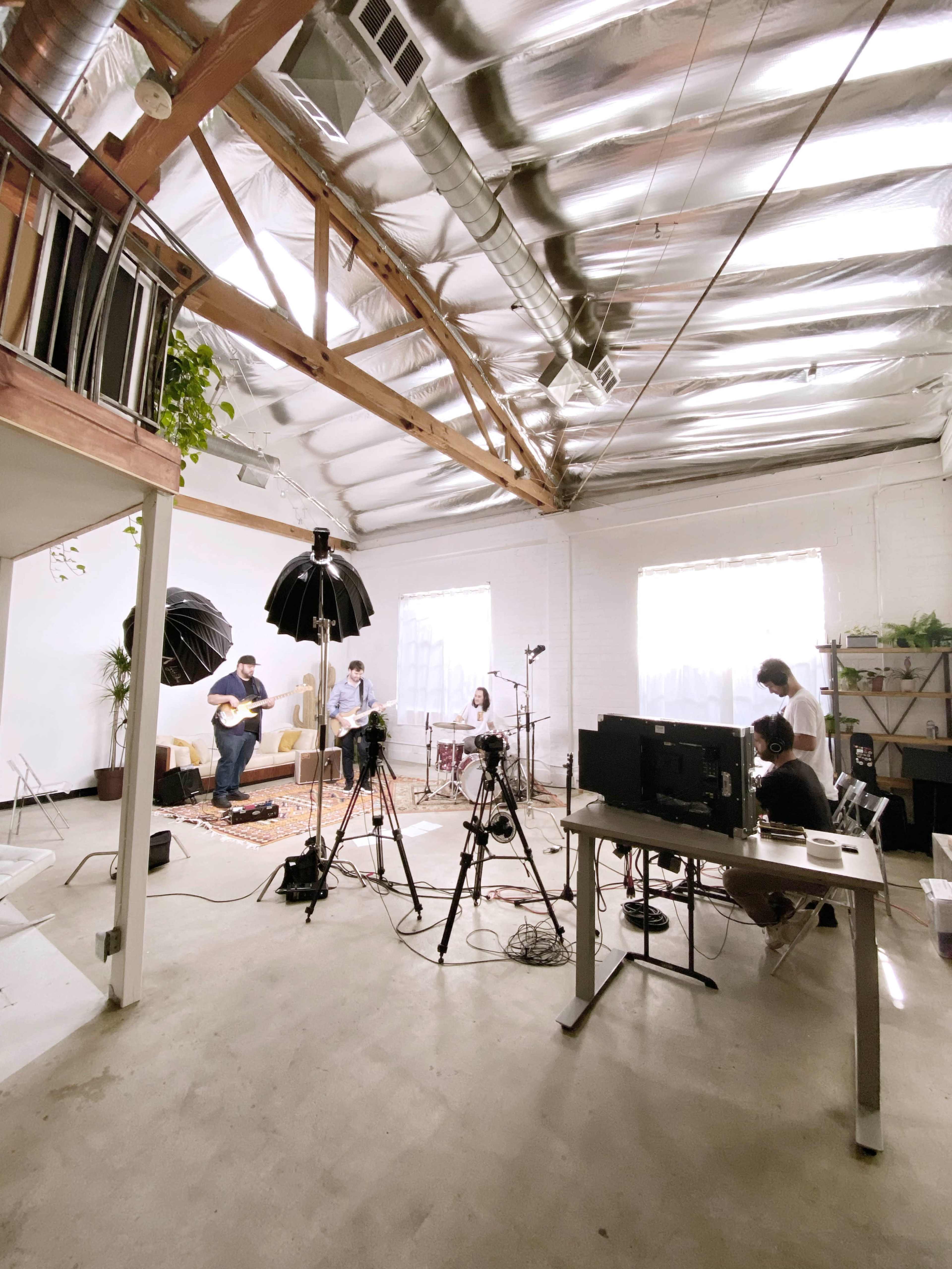 A group of musicians is performing in a spacious studio equipped with cameras and lighting.