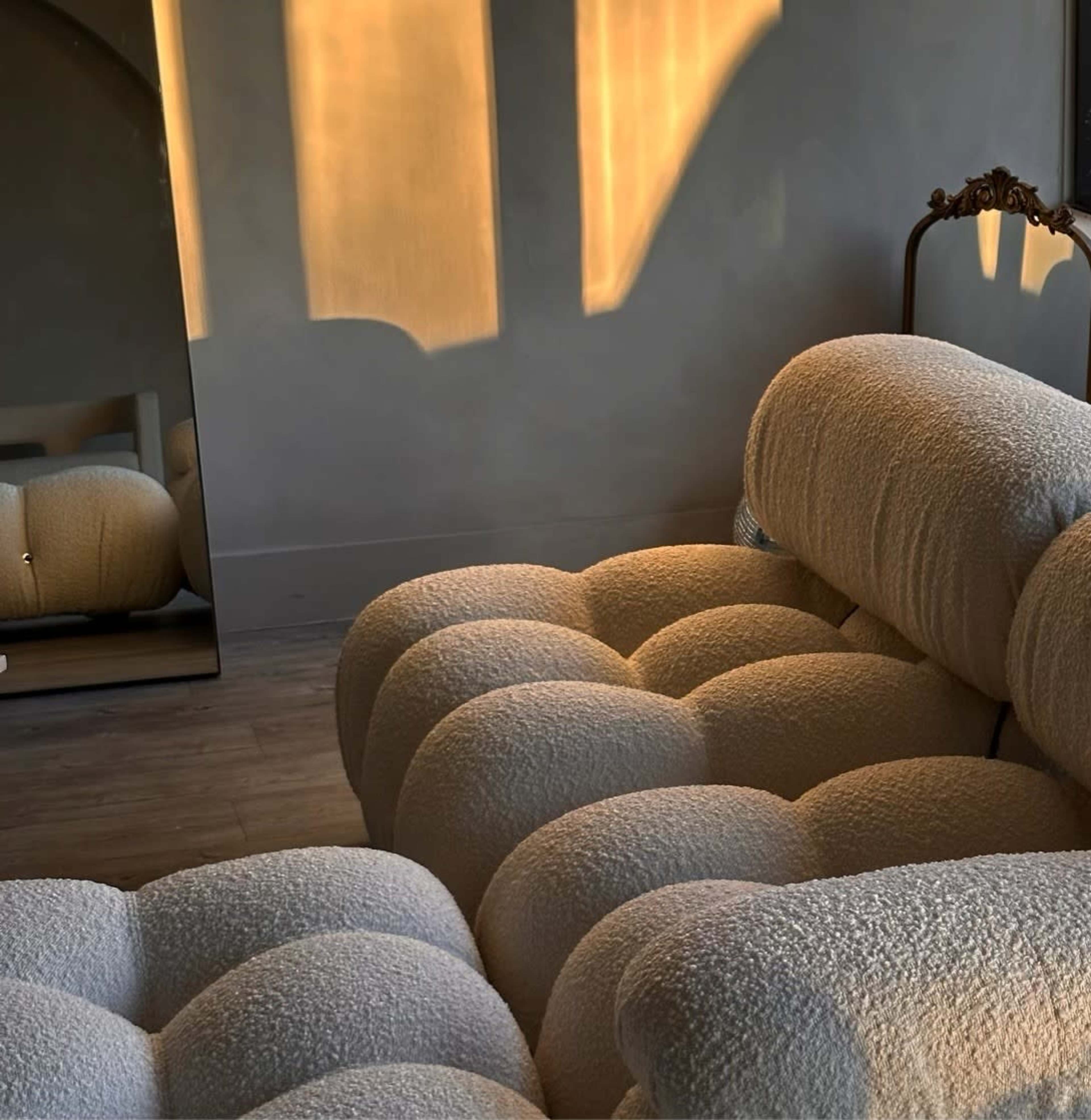 A plush, textured couch in a softly lit room with a mirror reflecting light.