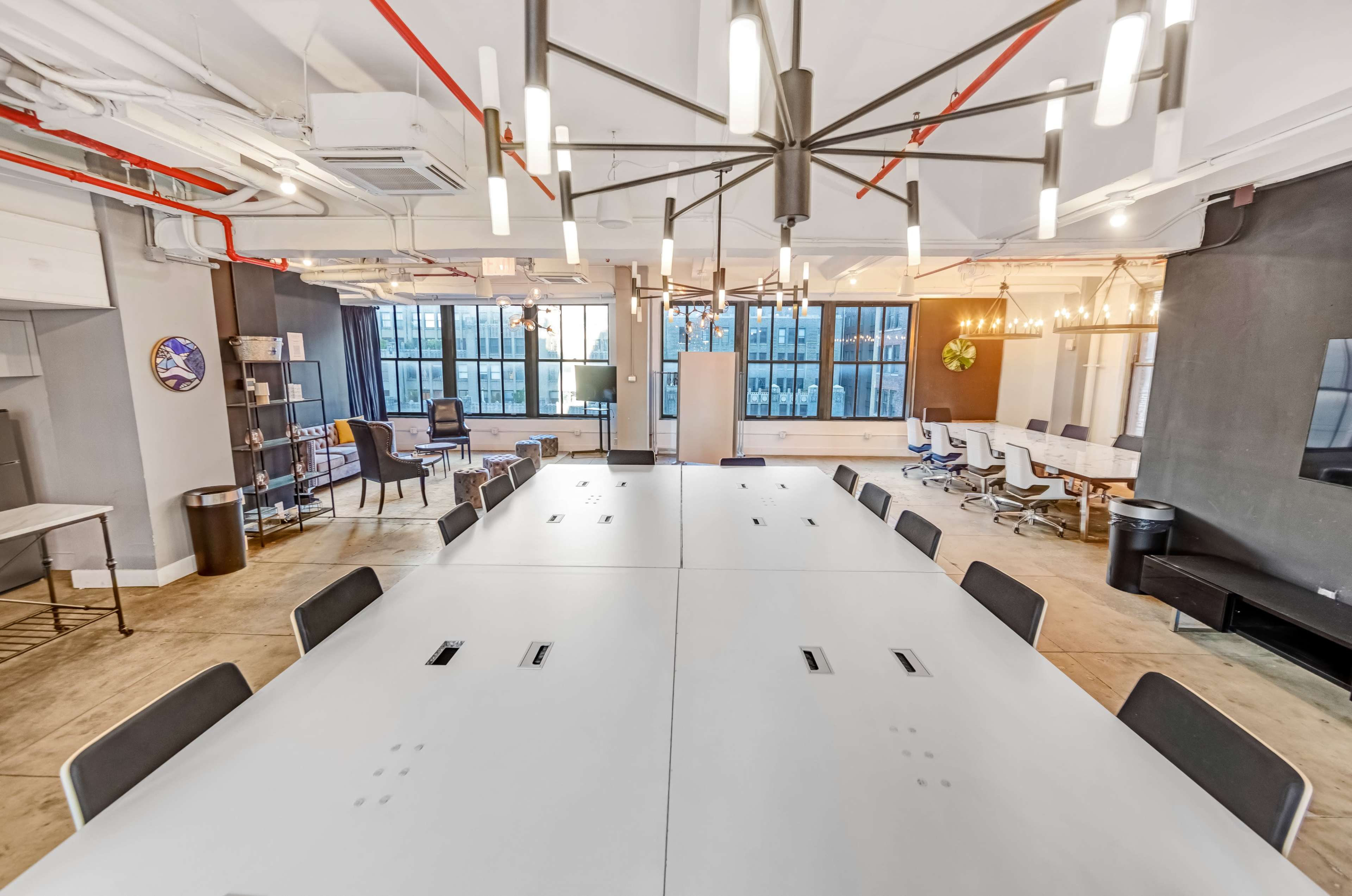 A spacious modern office features a large rectangular table surrounded by chairs, with large windows providing a view of the city skyline.