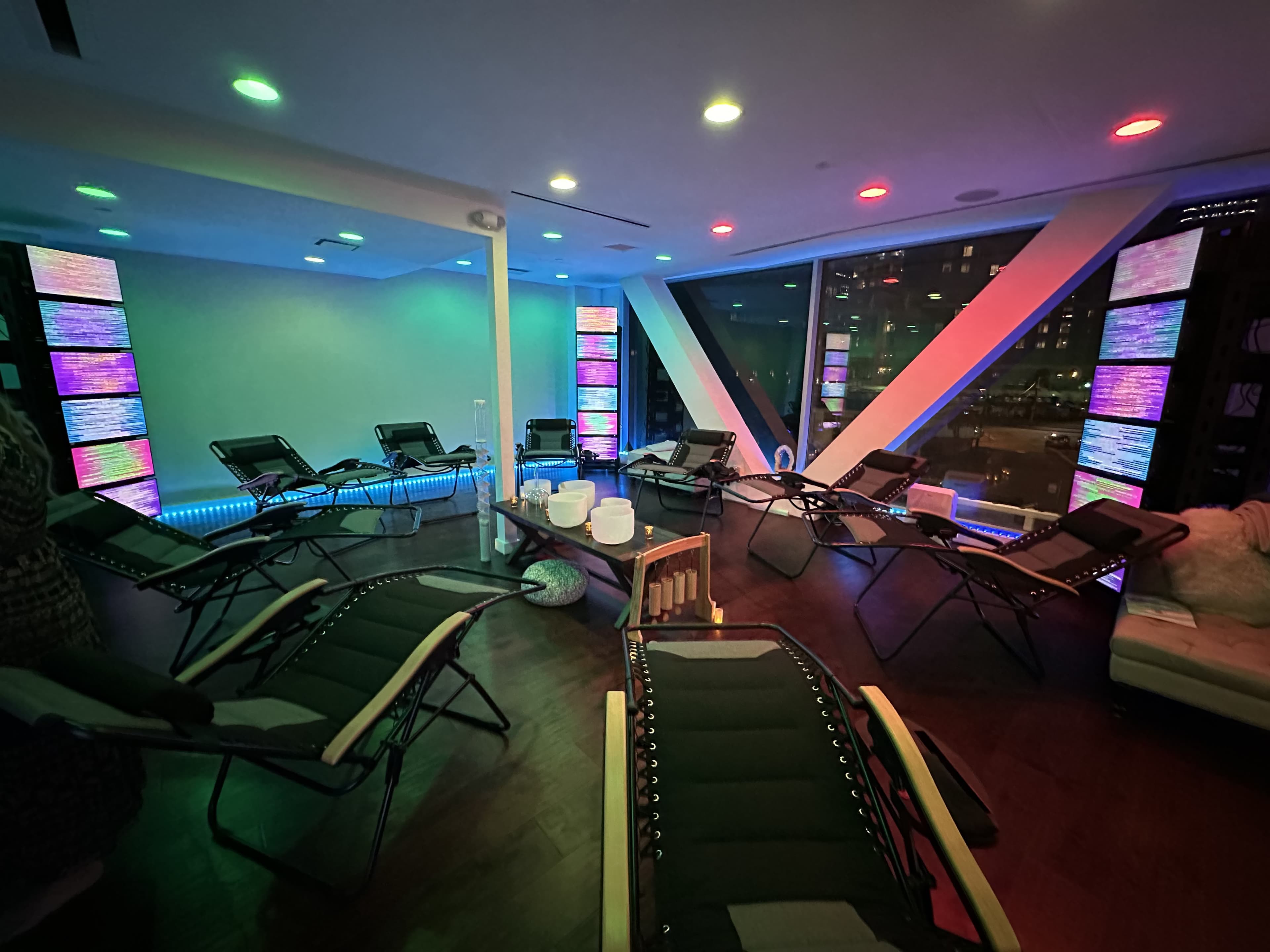 A modern relaxation room with reclining chairs, illuminated walls, and ambient lighting.