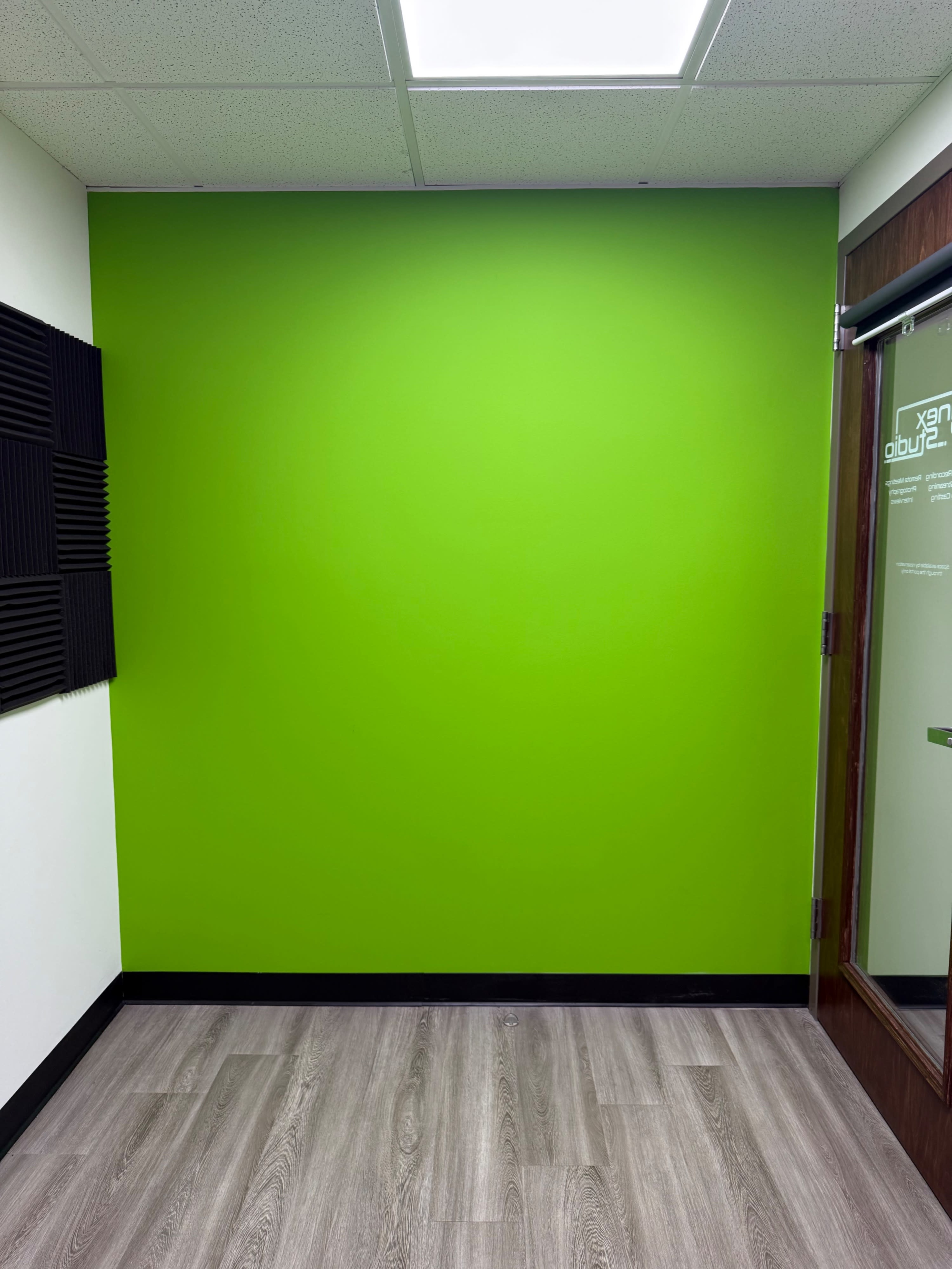 The image shows a bright green wall in a room with wooden flooring and a glass door.