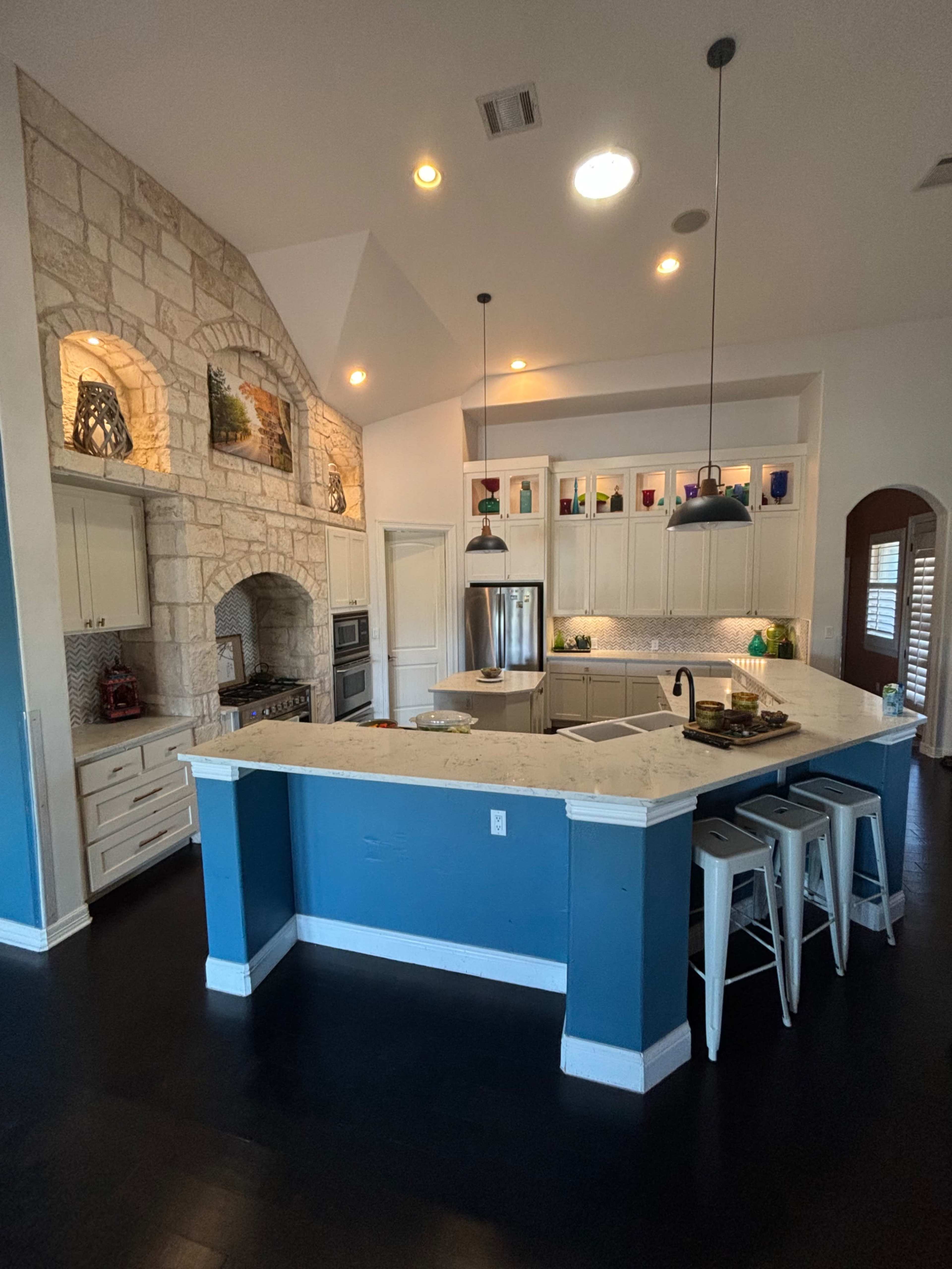 A modern kitchen with a large island, stone wall accents, and stainless steel appliances.