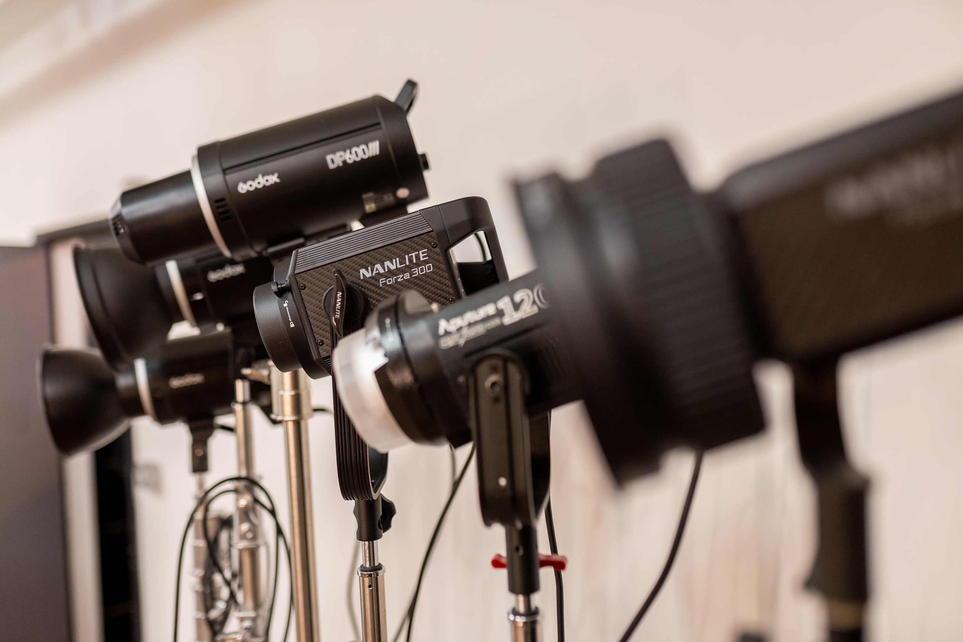 A collection of studio lighting equipment arranged in a row on stands.