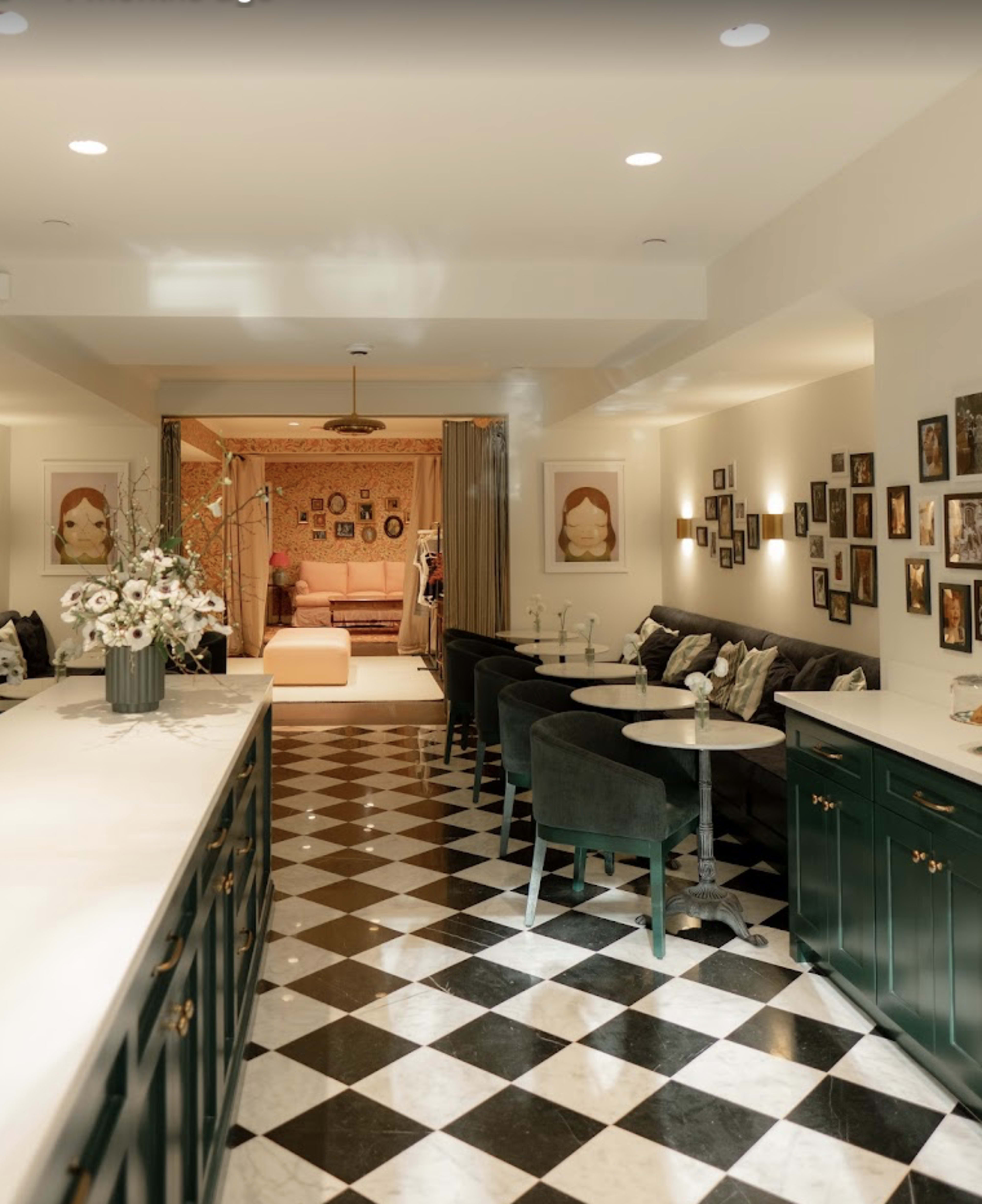 A stylish indoor space features a black and white checkered floor, green cabinets, and a cozy seating area with artwork on the walls.