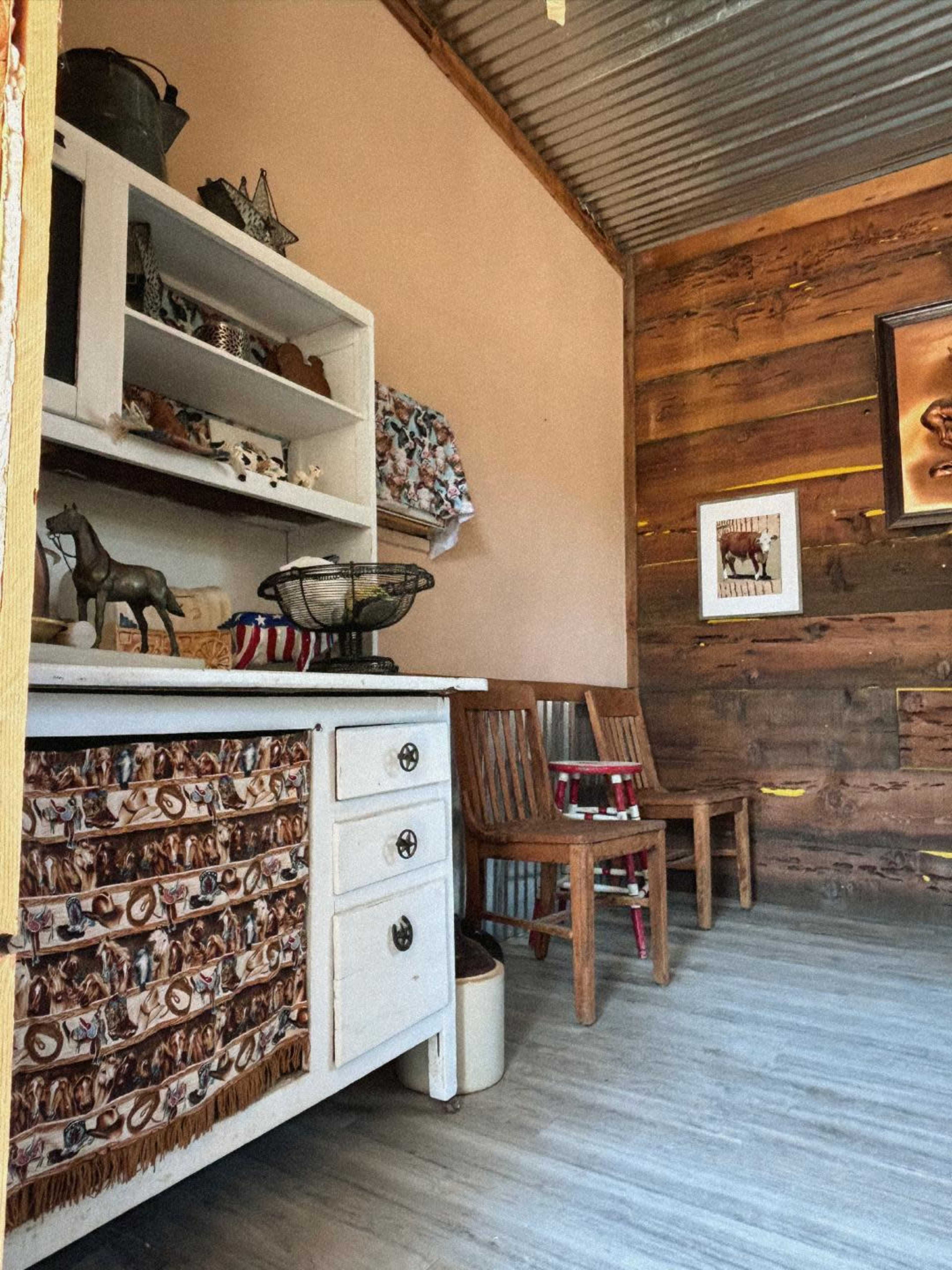 A cozy room with a white cabinet, wooden walls, and two chairs positioned in a corner.